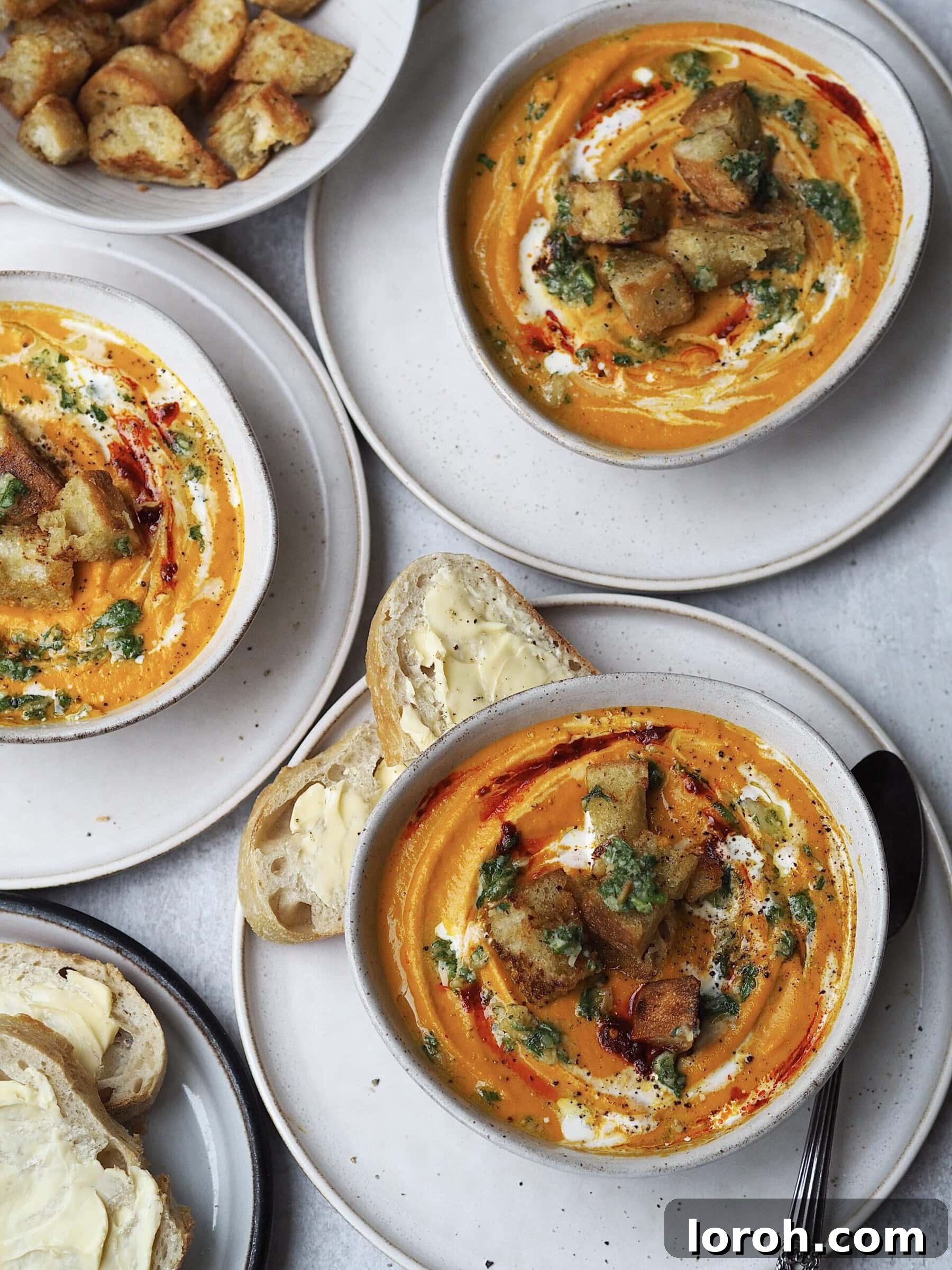 Smoky Harissa Carrot Velouté 12 Grey bowls of carrot soup topped with homemade pesto and croutons.