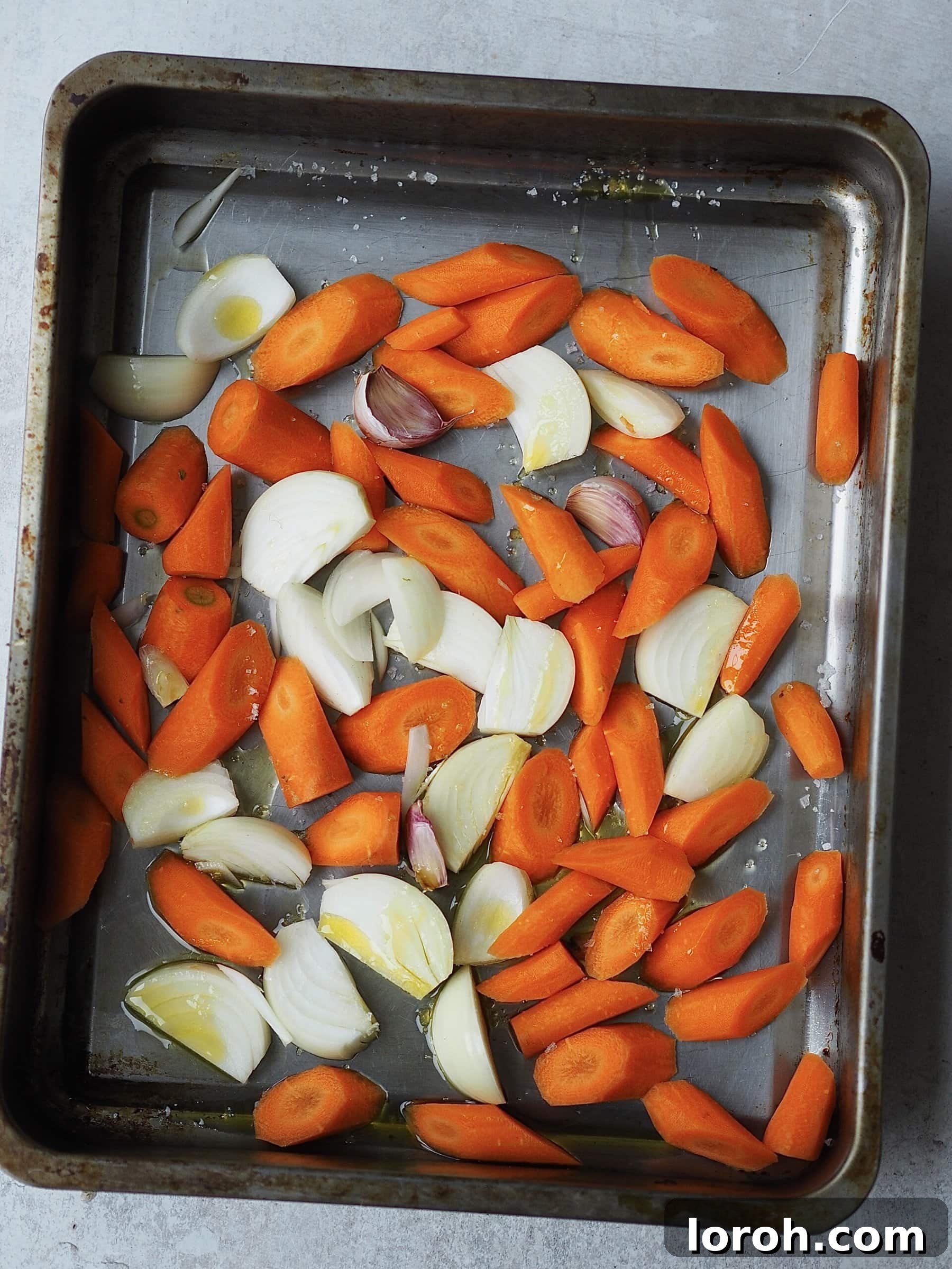 Smoky Harissa Carrot Velouté 5 Roasting tray of chopped carrots, onions and garlic.