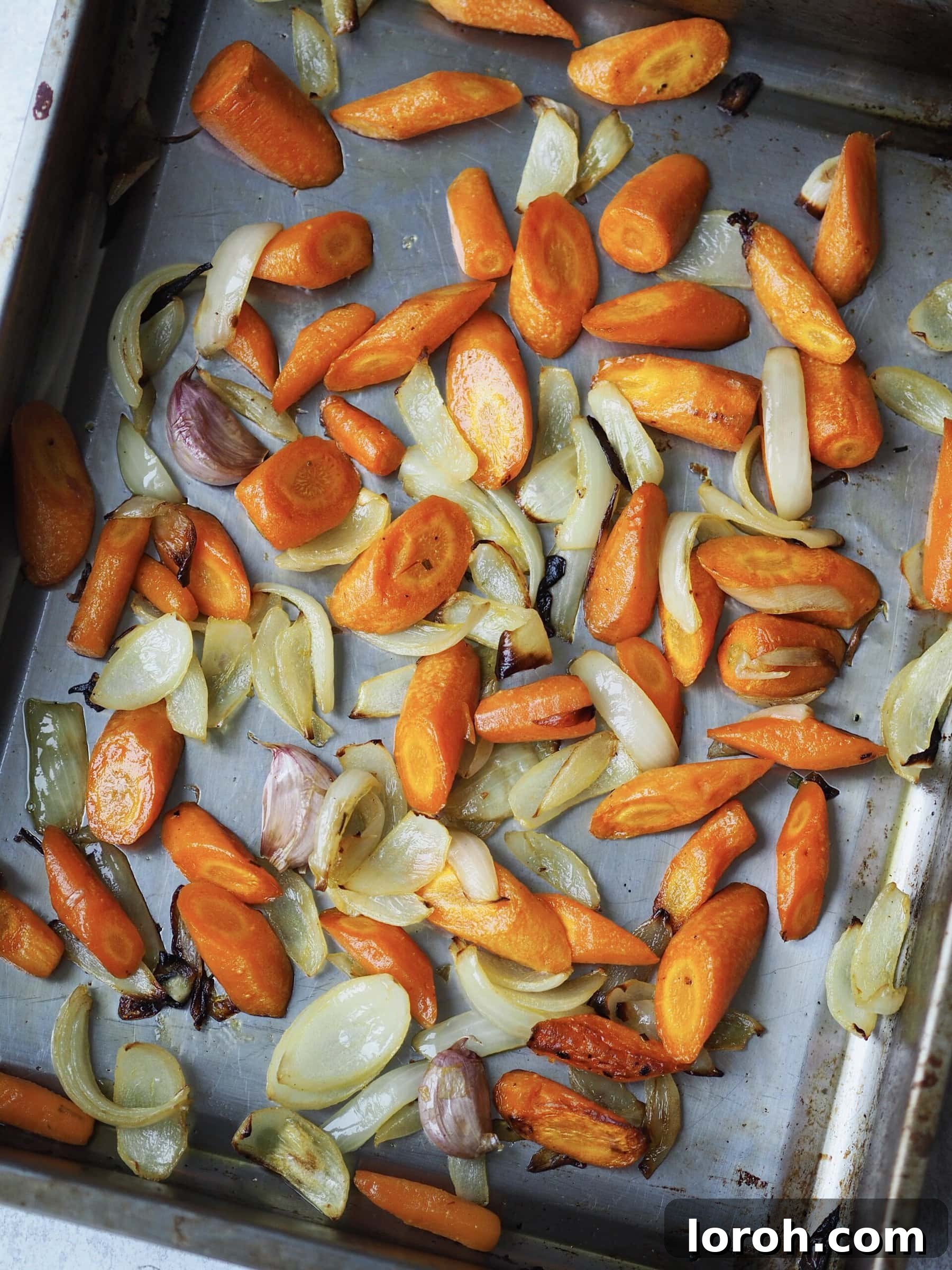Smoky Harissa Carrot Velouté 6 Roasted carrots, onions and garlic cloves on a roasting tray.