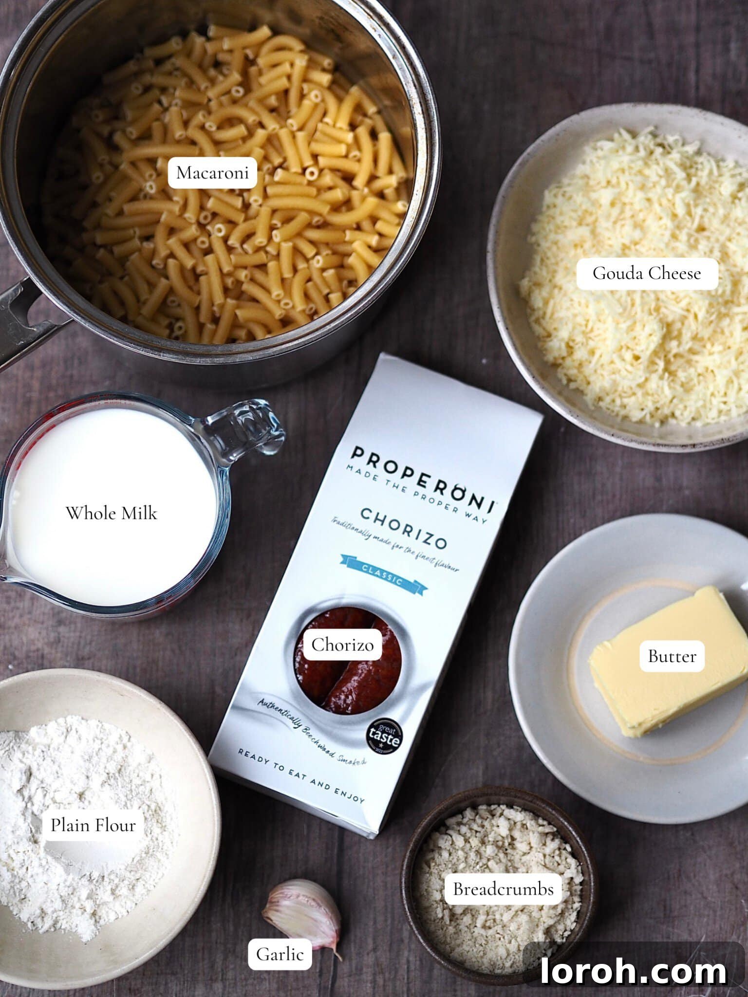 Decadent Gouda Mac and Cheese 3 Collection of labeled ingredients for making Gouda Mac and Cheese, including gouda, macaroni, chorizo, butter, milk, flour, garlic, and breadcrumbs.