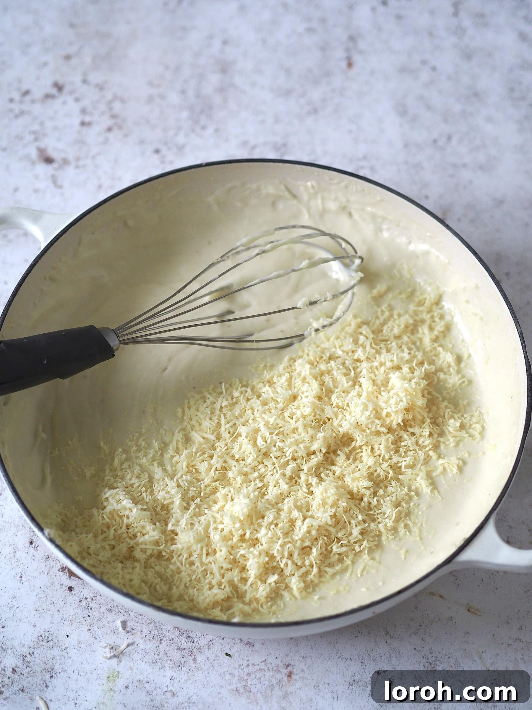 Decadent Gouda Mac and Cheese 7 Grated Gouda cheese being stirred into the creamy white sauce in a pan, melting smoothly.
