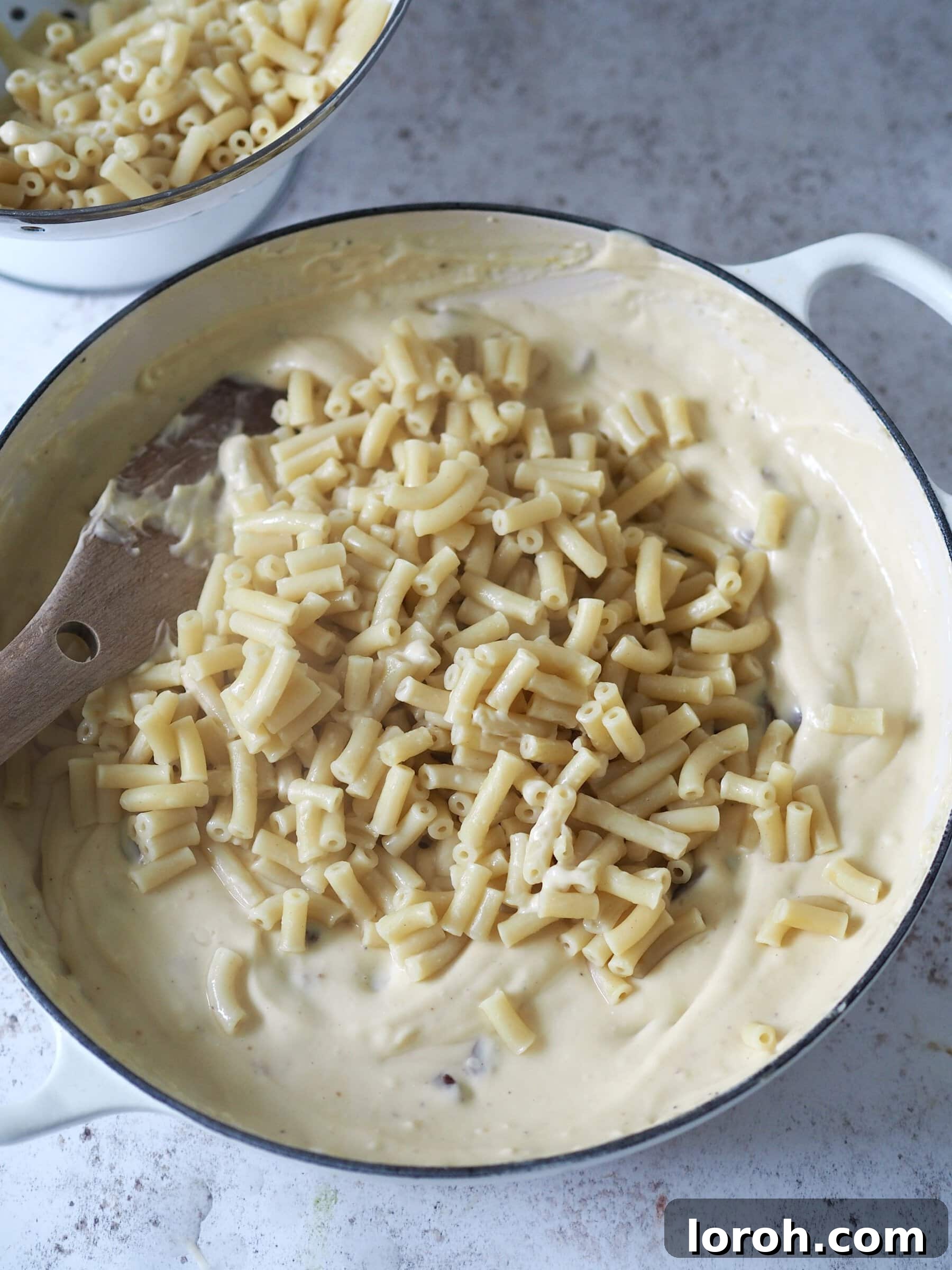 Decadent Gouda Mac and Cheese 8 Boiled macaroni pasta being mixed thoroughly with the Gouda cheese sauce in a large bowl.
