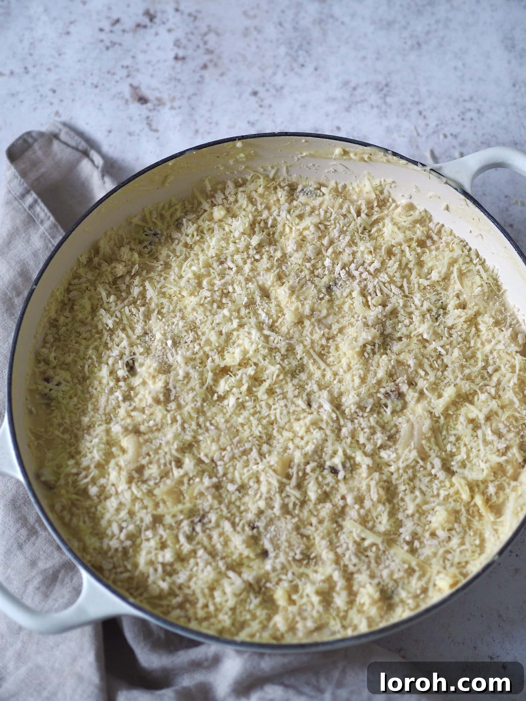 Decadent Gouda Mac and Cheese 9 Gouda Mac and Cheese in an ovenproof dish, topped with grated cheese and breadcrumbs, ready for baking.