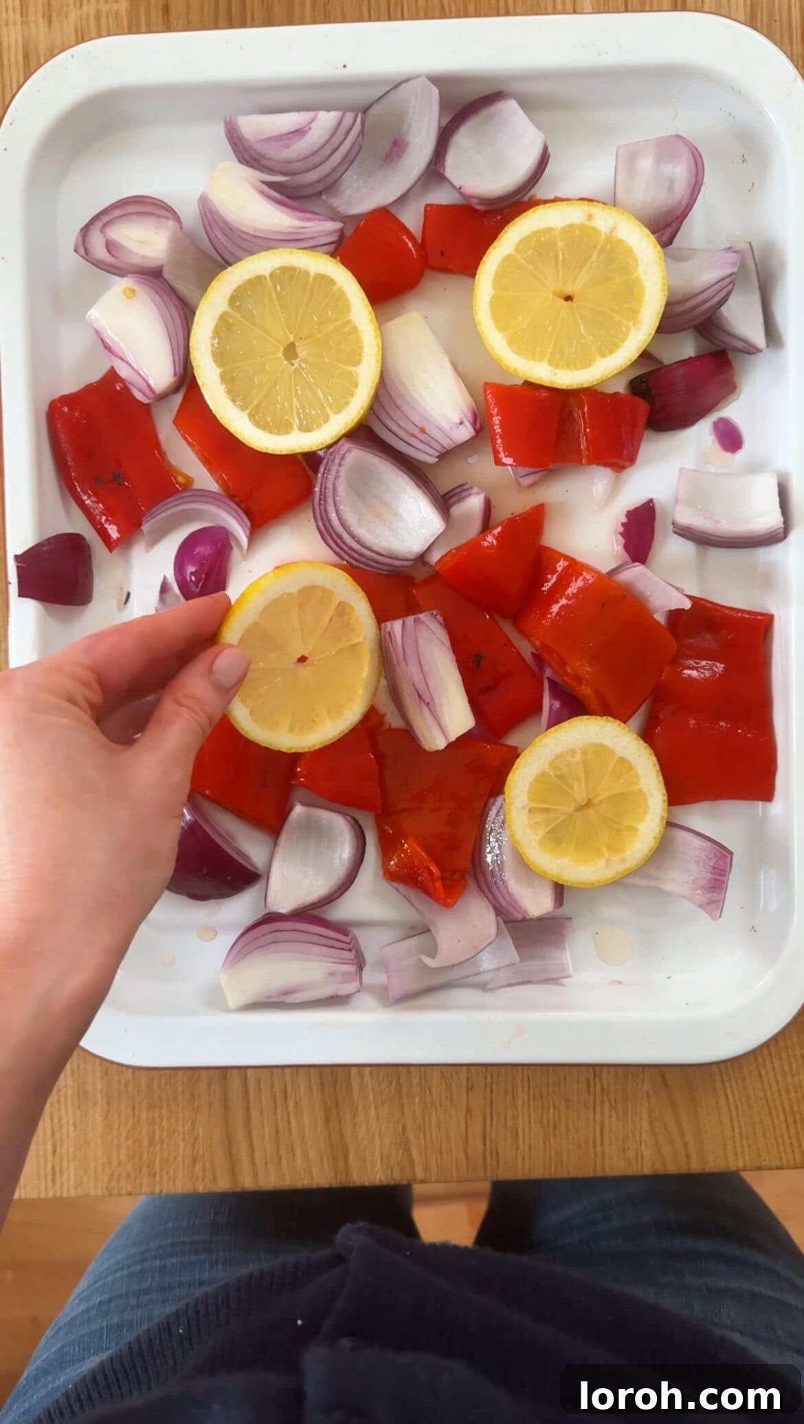 Step two: arranging onions, peppers, and lemon slices in a roasting tin