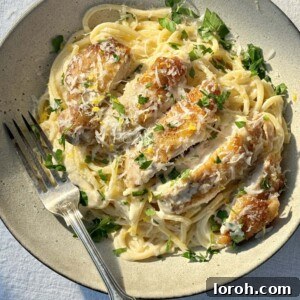 Velvety Chicken Pasta 12 A beautifully plated creamy chicken pasta in a bowl, garnished with fresh parsley and lemon zest, ready to be served.