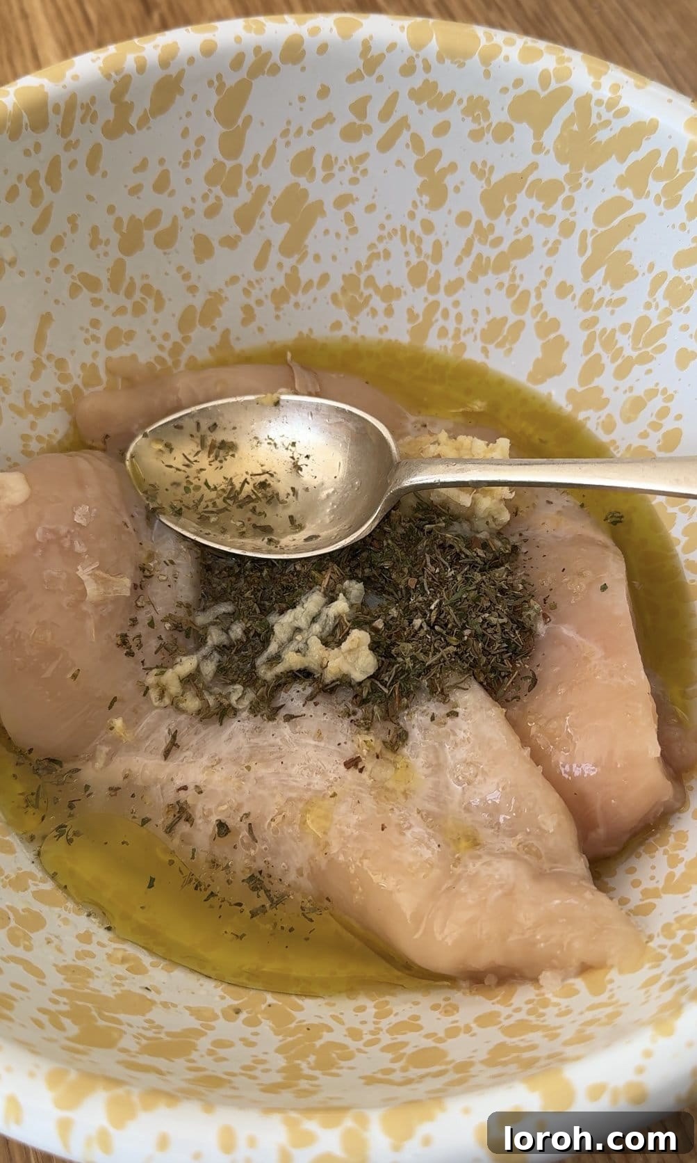 Velvety Chicken Pasta 4 Chicken breasts being marinated in a bowl with Italian herb seasoning, salt, and olive oil.