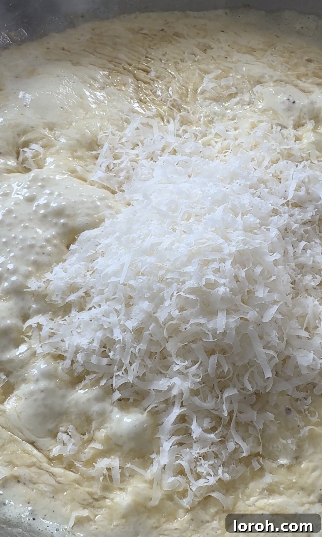 Velvety Chicken Pasta 8 Grated Parmesan cheese being stirred into the simmering creamy sauce for depth of flavor.