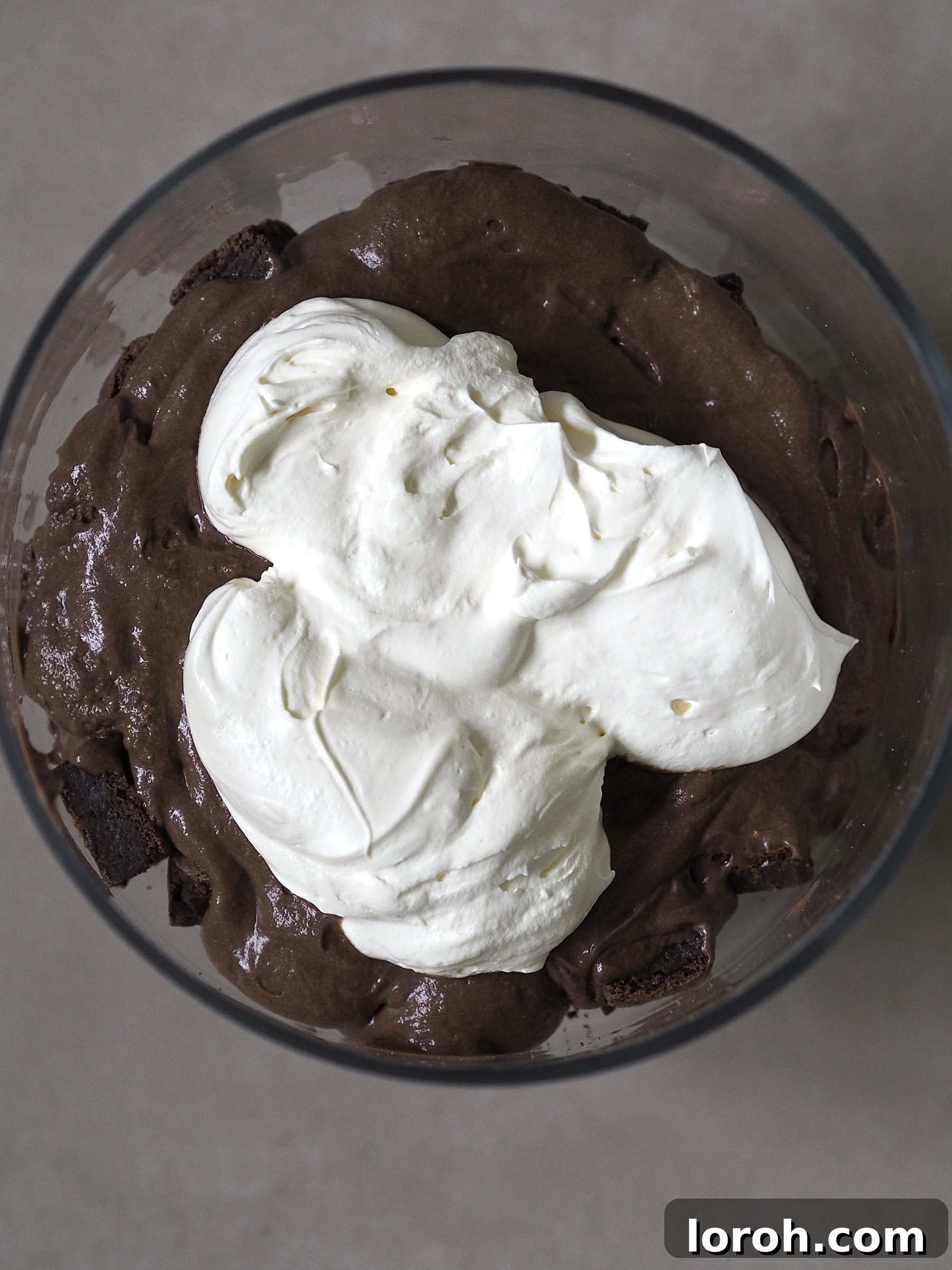 Layering rich chocolate mousse, fluffy whipped cream, and gooey caramel over the brownie base in a trifle dish.
