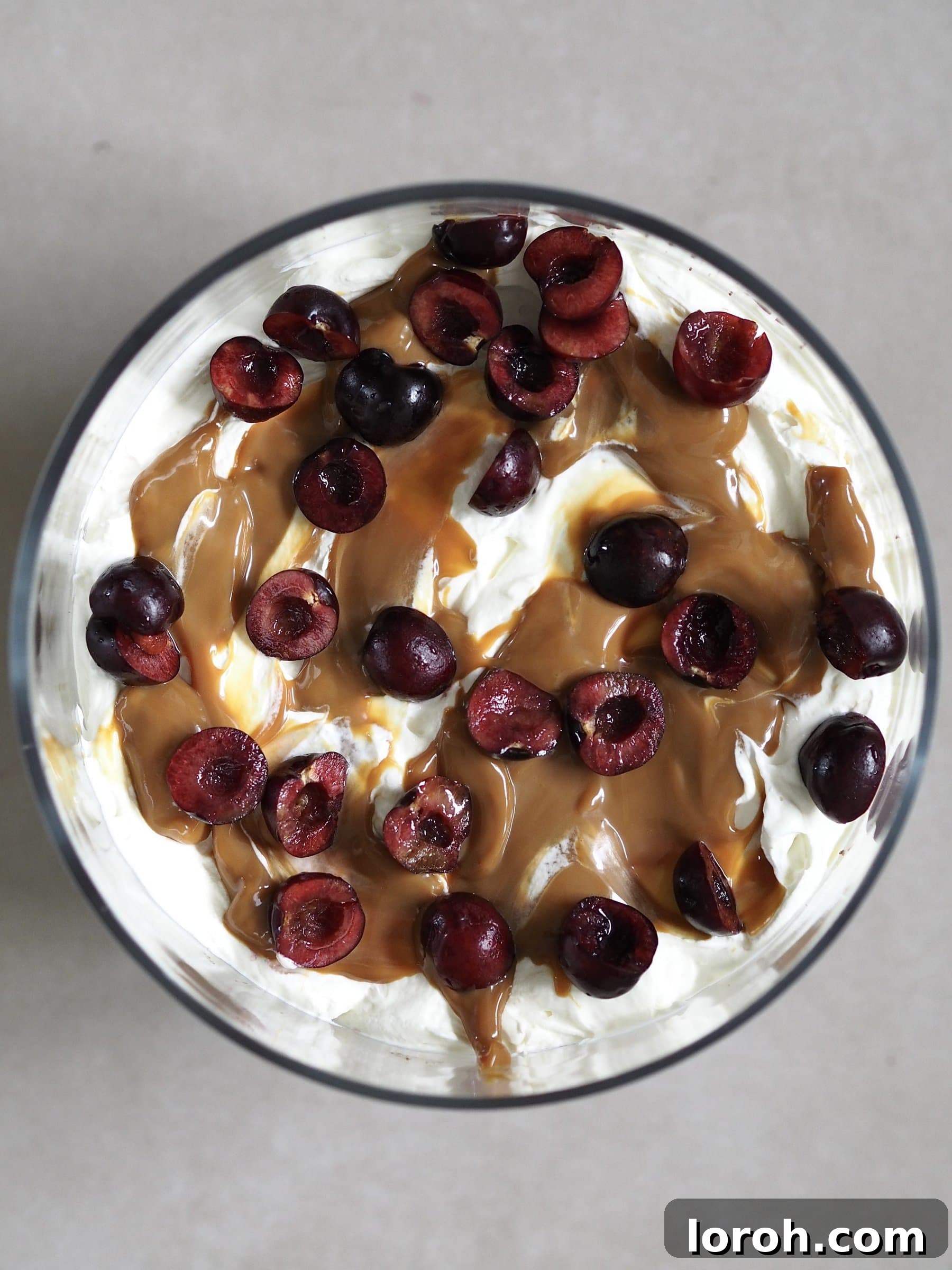 The completed Chocolate Brownie Trifle with all layers, topped with whipped cream, fresh cherries, mint, and chocolate shavings, ready to be chilled.