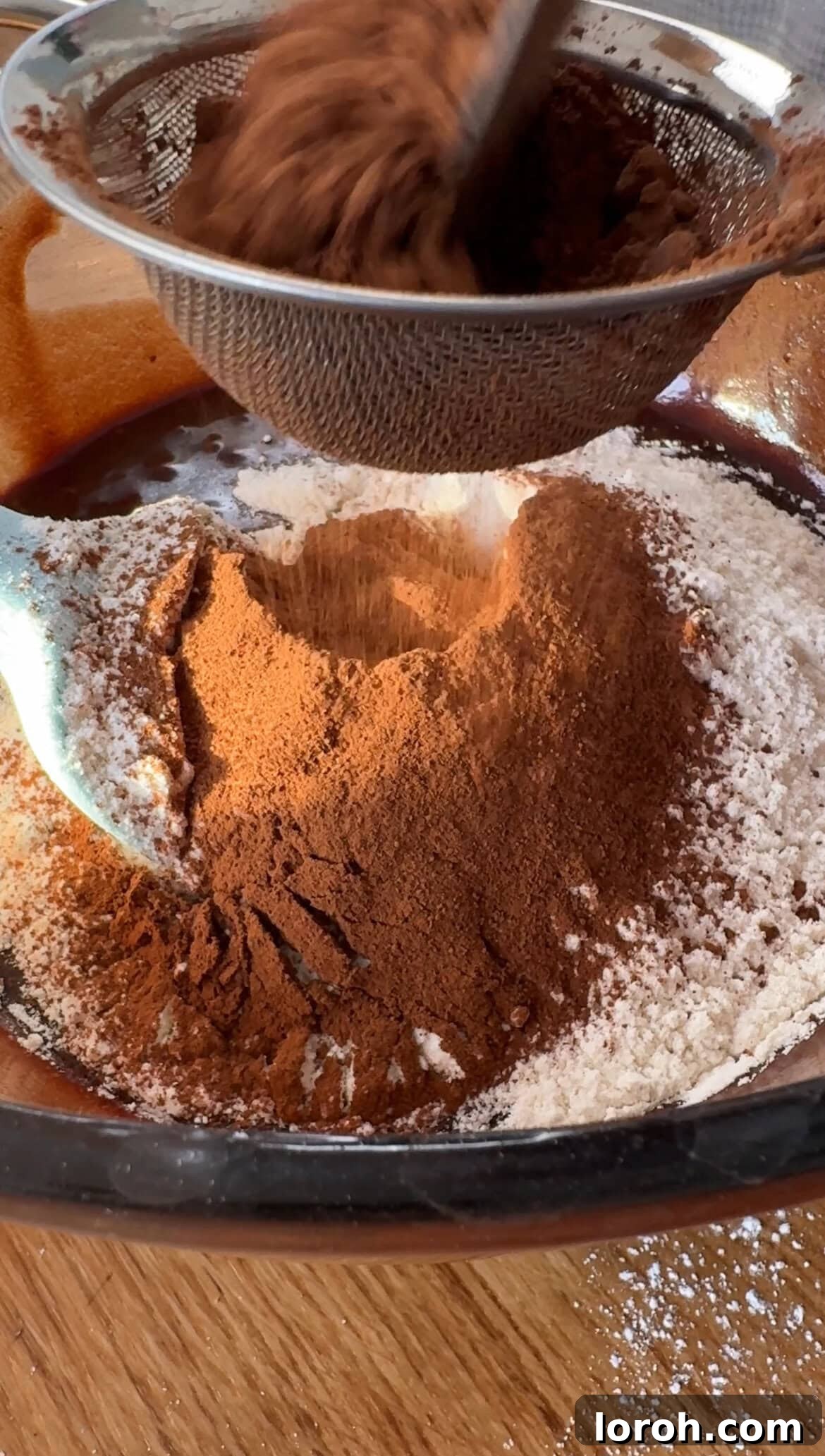 Sifting plain white flour and cocoa powder into the wet chocolate brownie batter, with salt added.