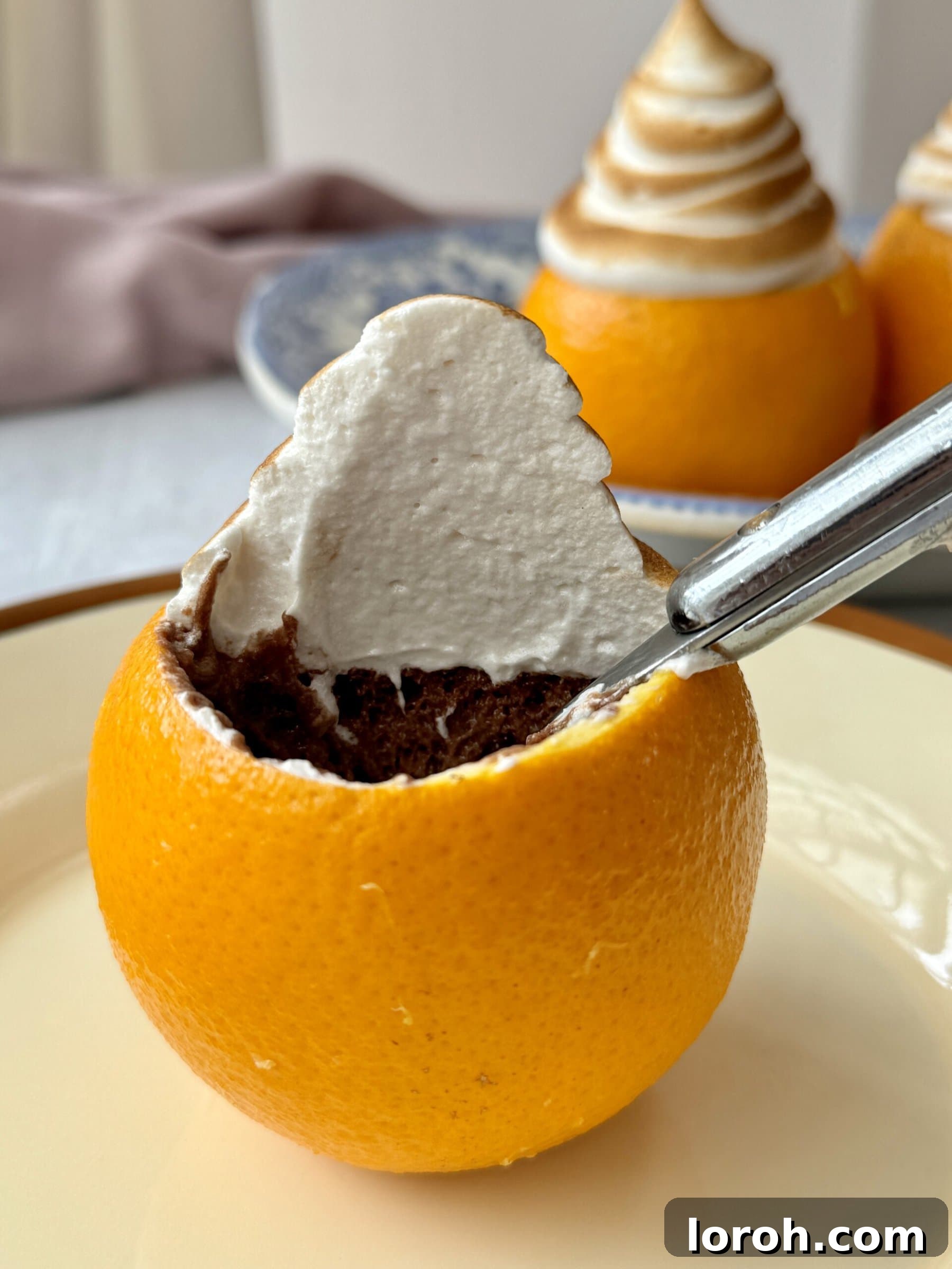 Citrus Cocoa Cloud 12 A close-up of the smooth, rich chocolate orange mousse in a delicate serving, adorned with a golden brown sugar meringue peak.