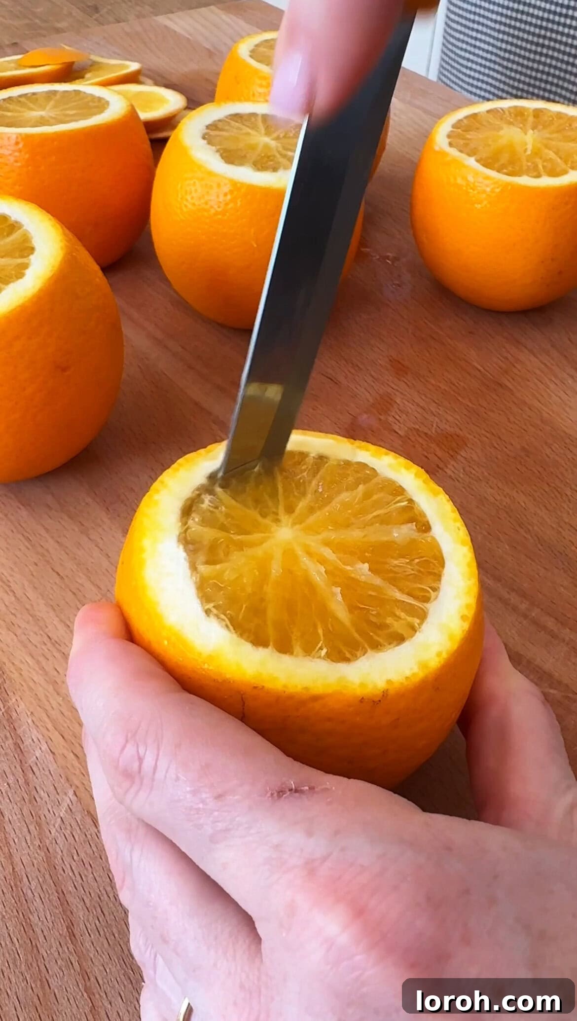 Citrus Cocoa Cloud 6 A knife cutting around the edge of an orange half, preparing it to be scooped out for mousse cups.