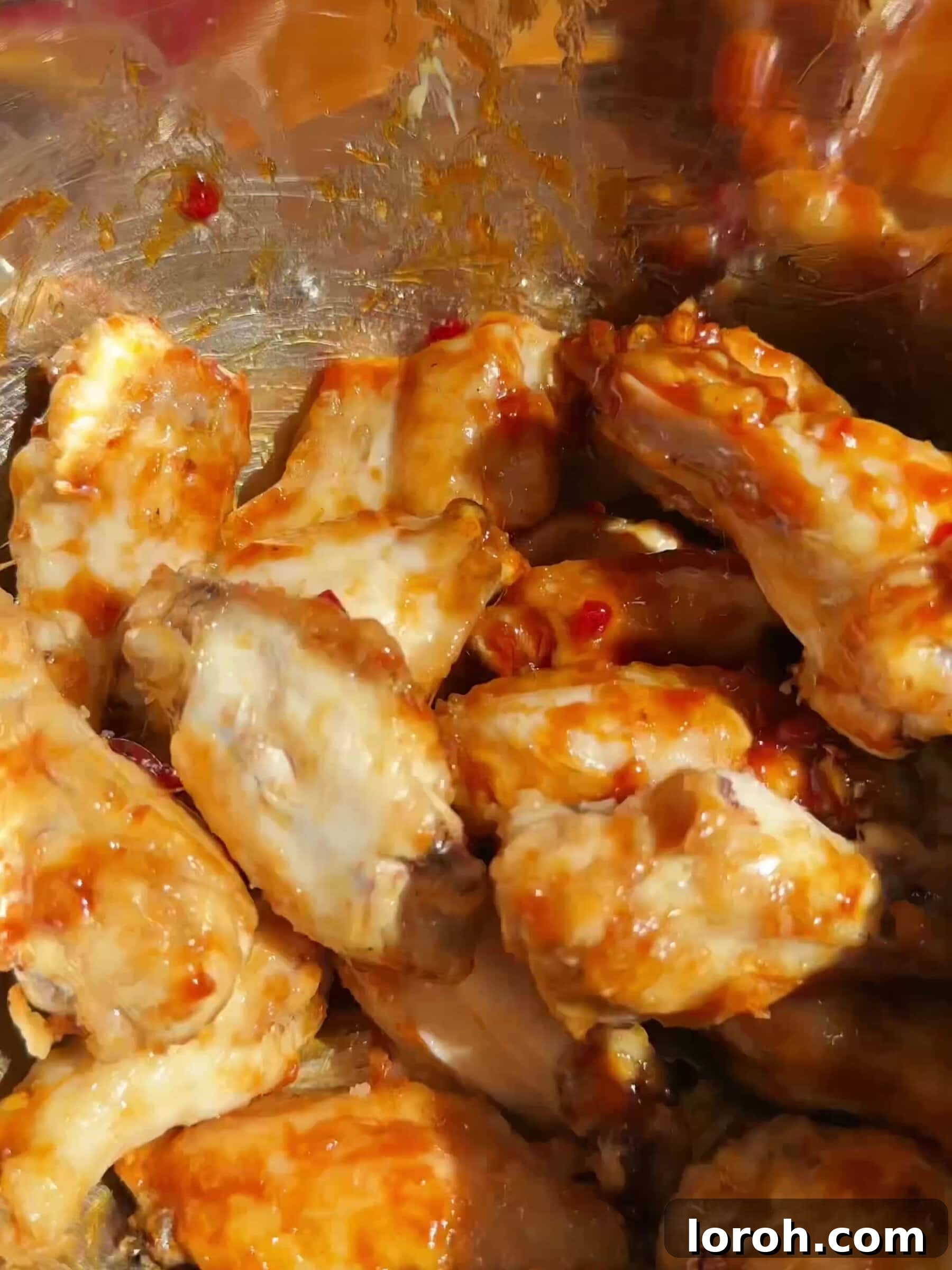 Tossing crispy chicken wings in the luscious hot honey sauce.