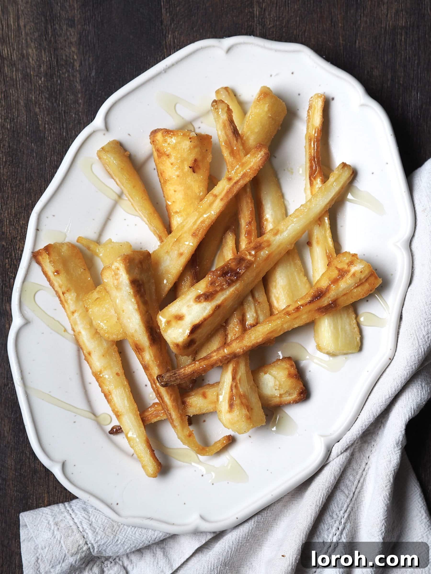 A white serving platter showcasing perfectly roasted parsnips, glistening with honey glaze.