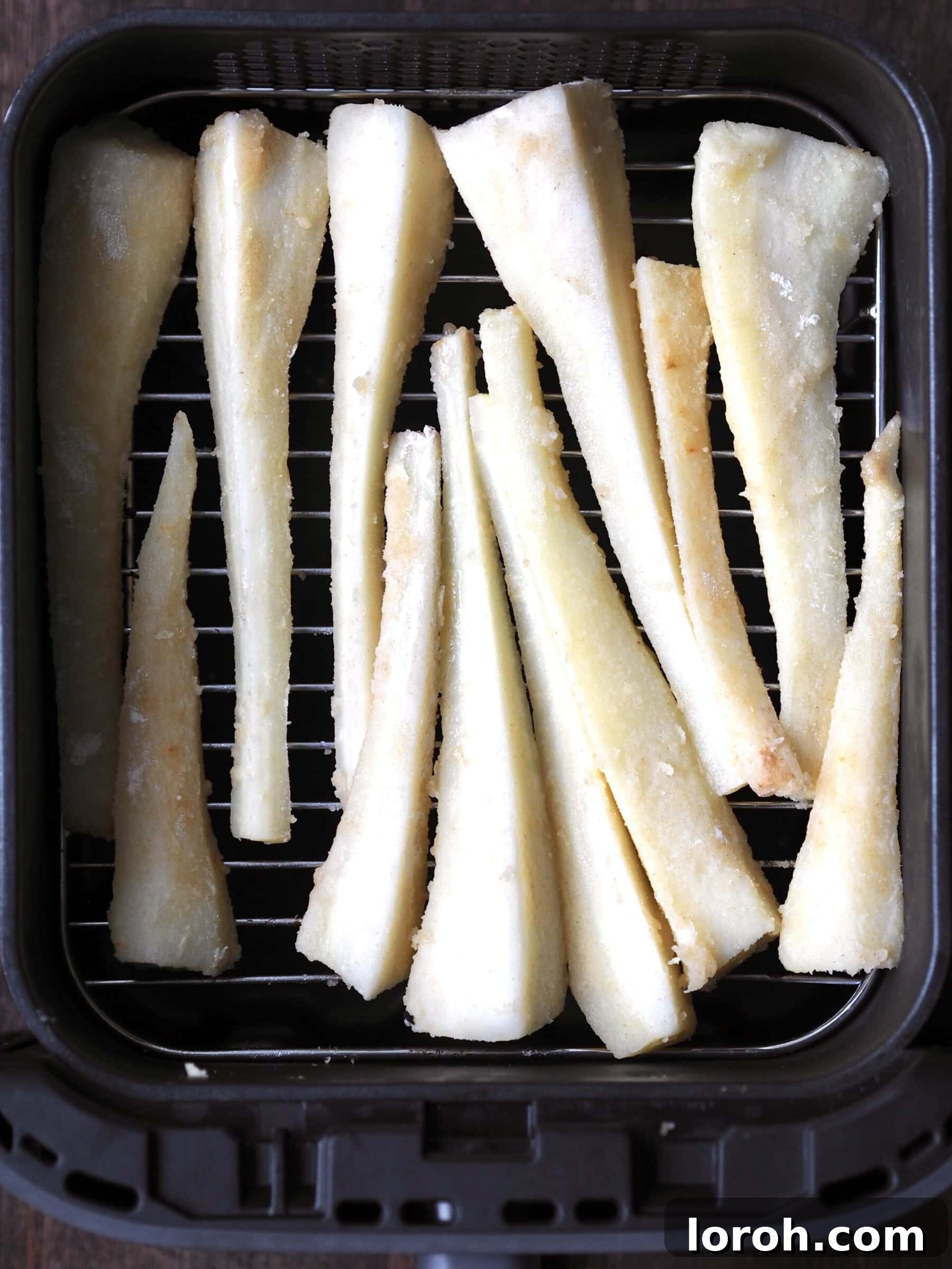 Flour, salt, and oil being tossed with par-boiled parsnips in a saucepan.