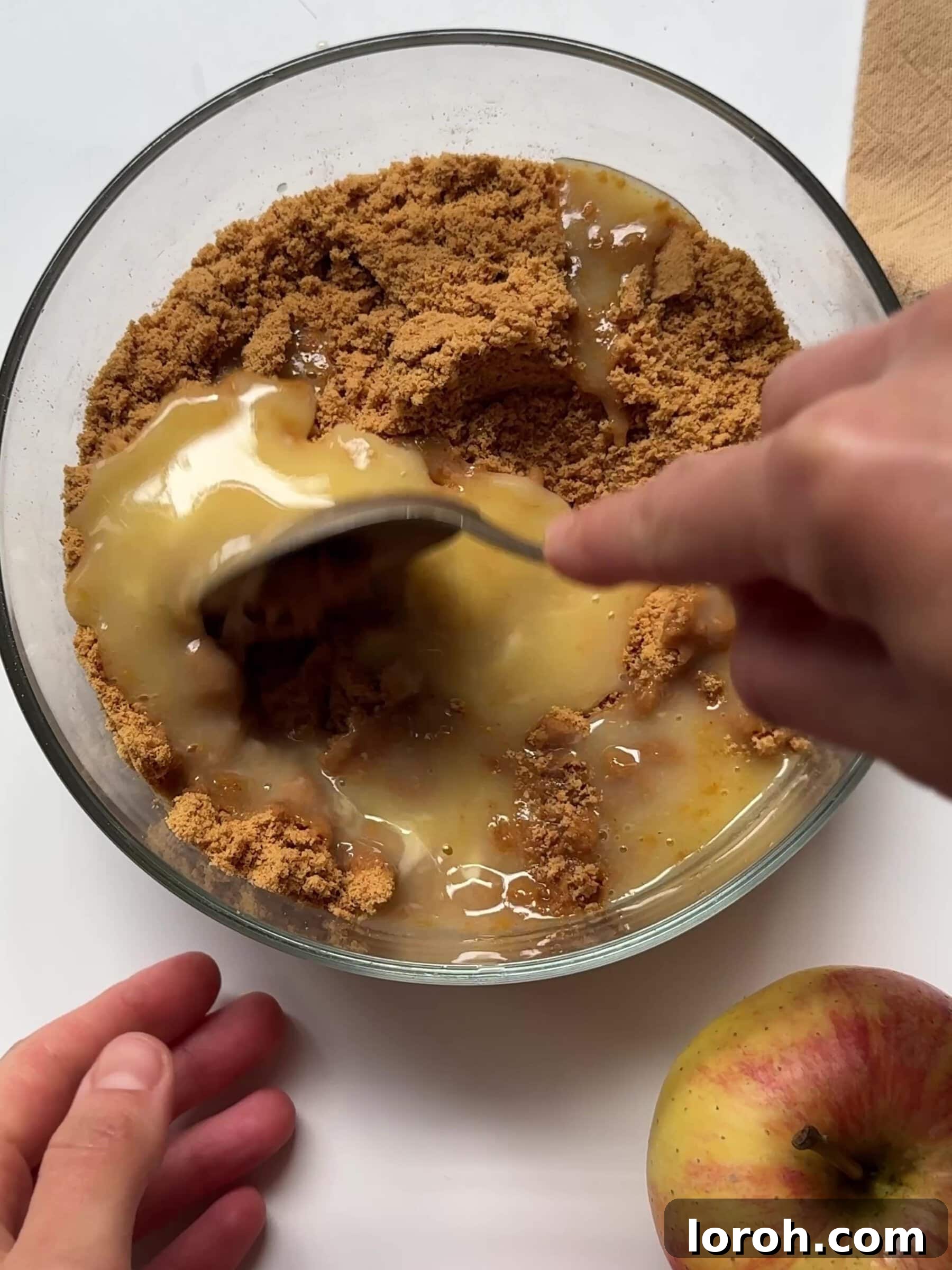 Melted butter being added to finely crushed biscuits in a food processor, creating a crumbly mixture.