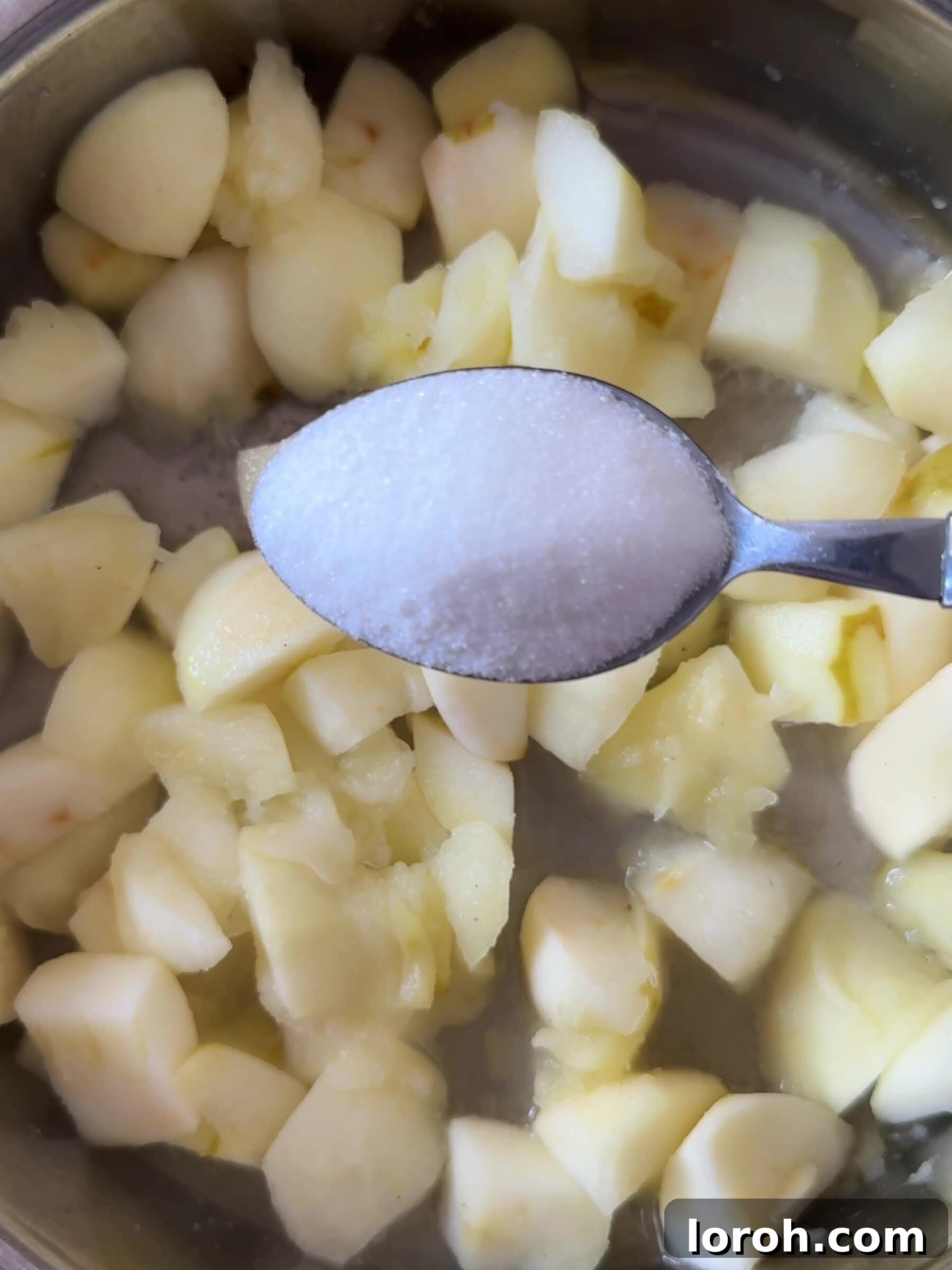 Warm Apple & Blackberry Crumble 5 Image showing caster sugar and lemon juice being added to softened apples in a pan.