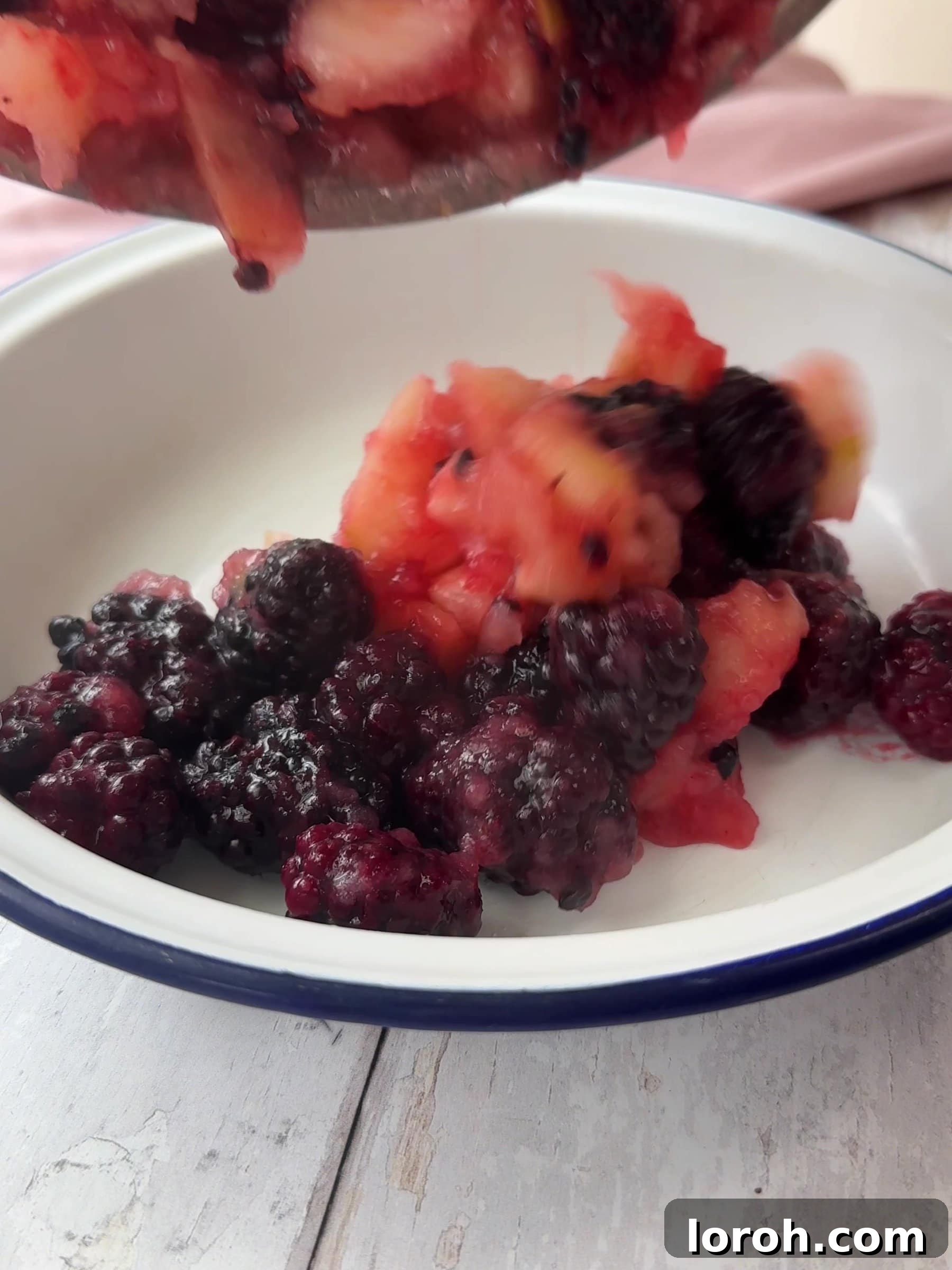 Spooning berries and apples into a baking dish