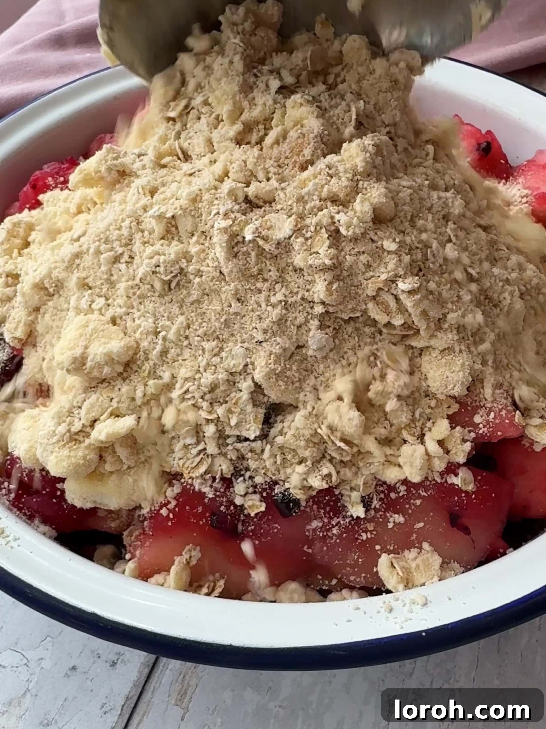 Tipping the crumble mixture over the fruit
