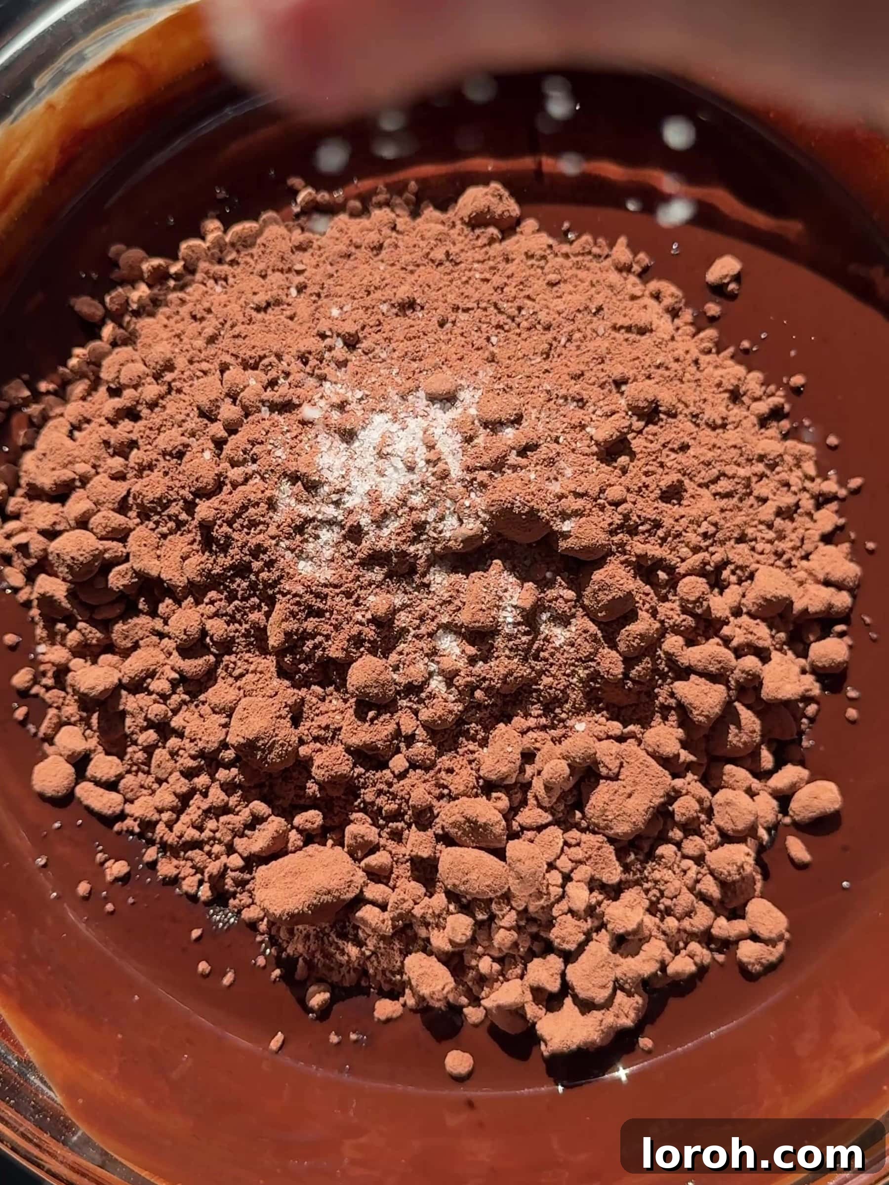 Adding cocoa powder and a pinch of salt to melted chocolate and butter mixture.