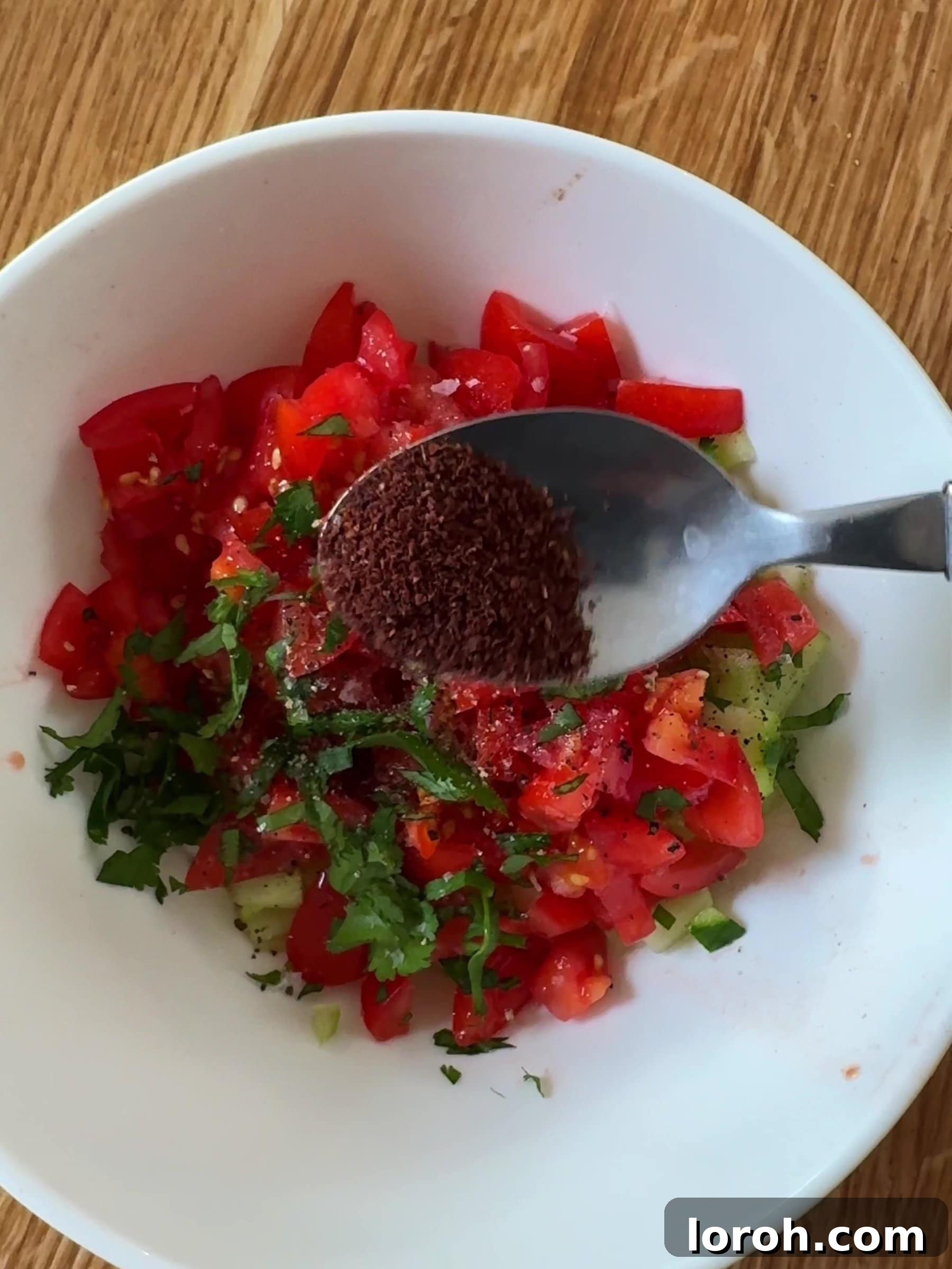 Golden Lamb & Couscous with Bright Herb Salad 8 Diced tomatoes and cucumbers being mixed in a bowl for the fresh salad.