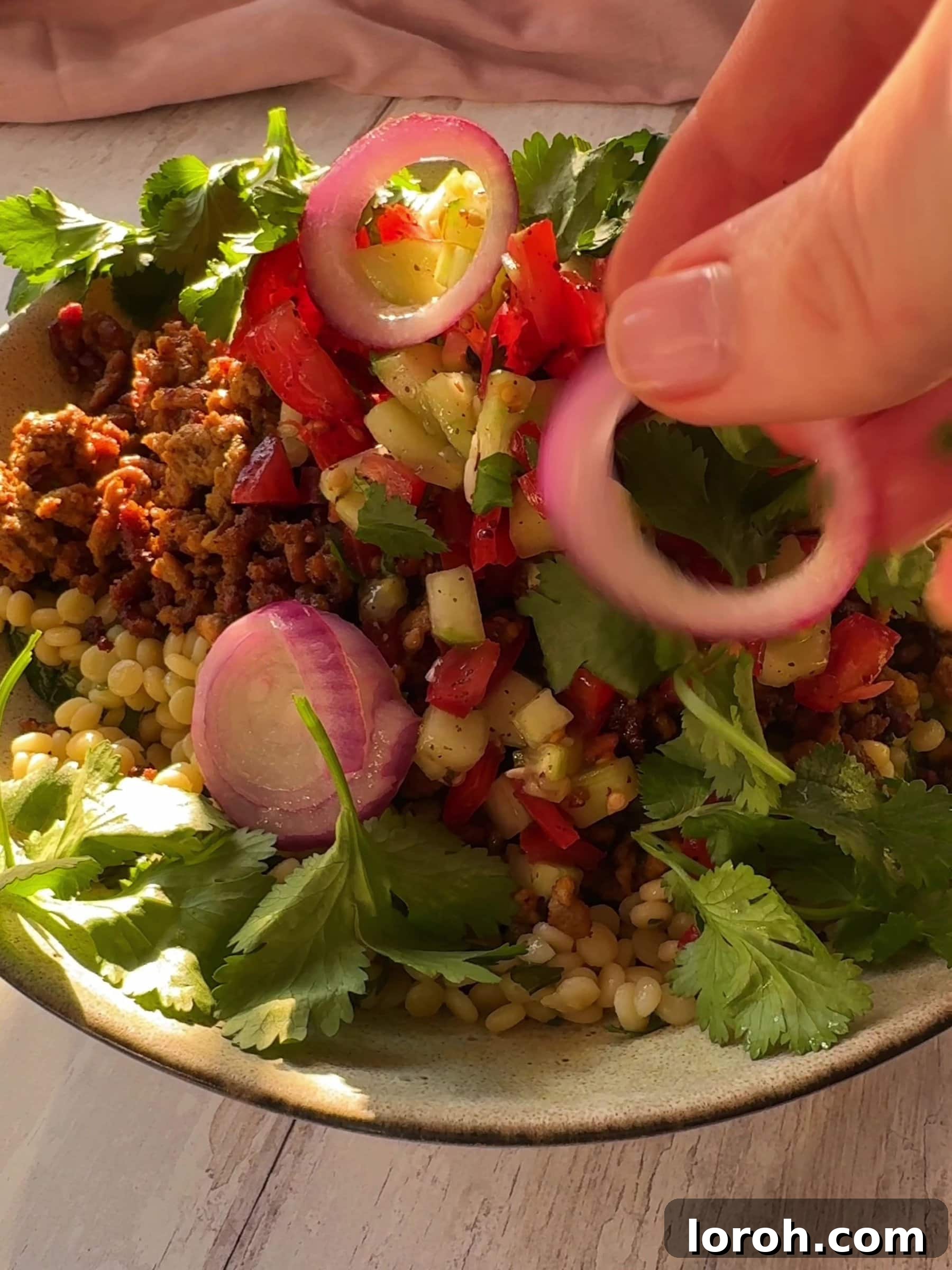 Golden Lamb & Couscous with Bright Herb Salad 9 A fully assembled bowl of crispy lamb mince with couscous, salad, and various toppings.