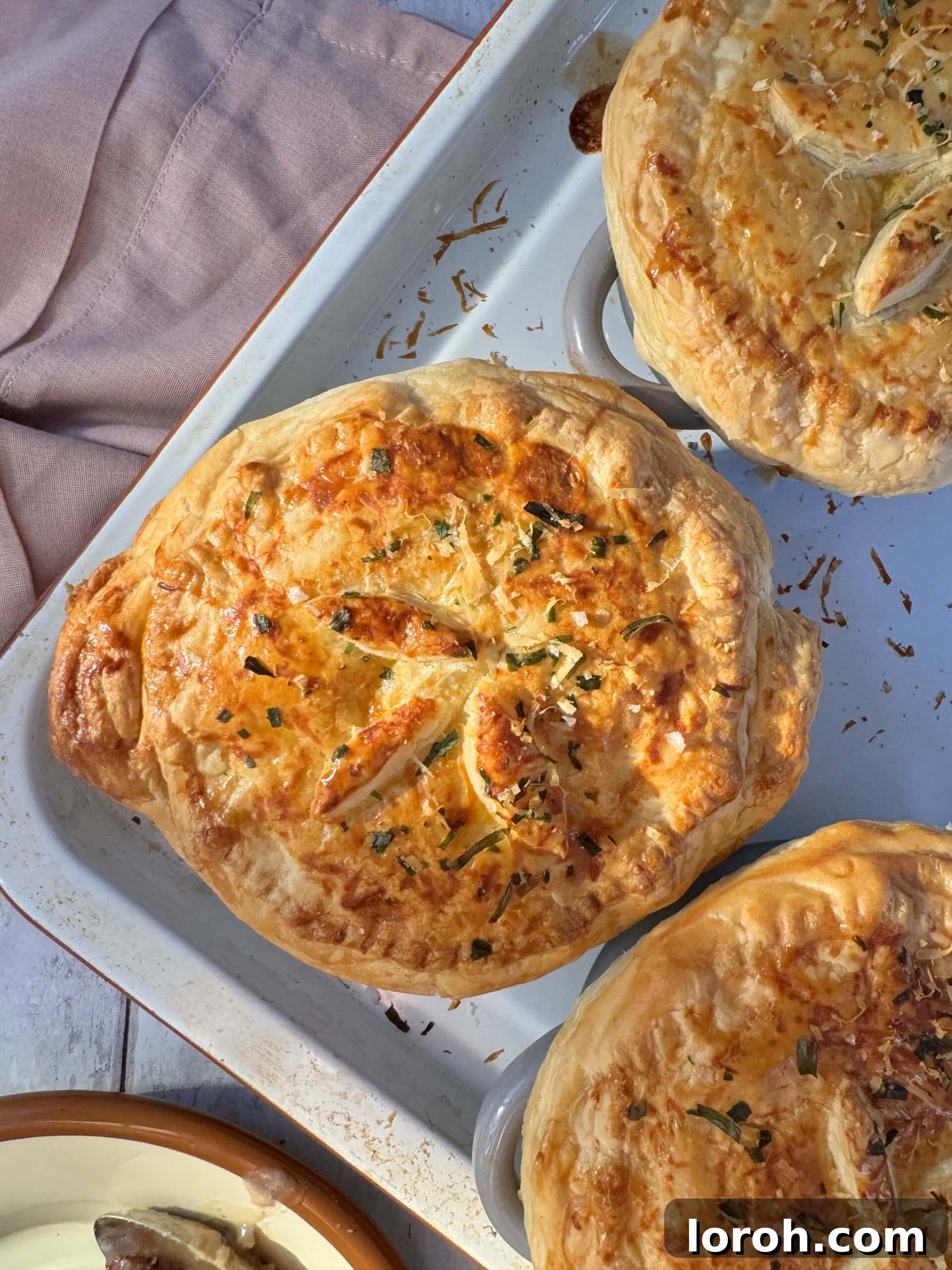 Six golden-brown chicken mini pot pies arranged neatly on a baking tray, ready to be served, showcasing their crispy pastry tops.