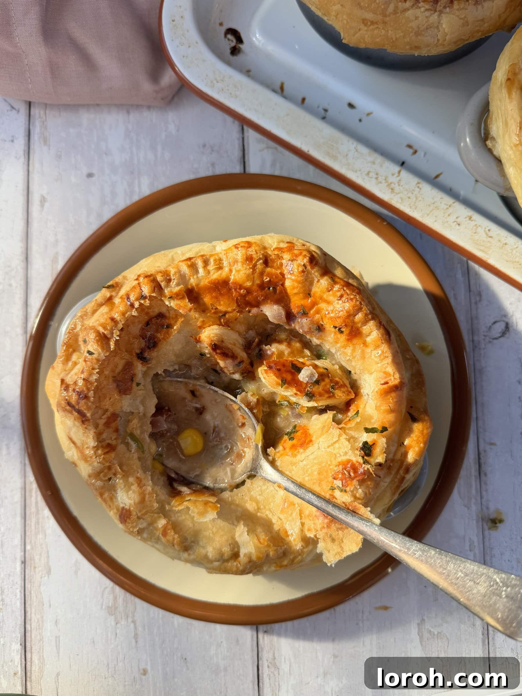 A single chicken mini pot pie with a spoon digging into the creamy filling, showing the rich texture and ingredients.