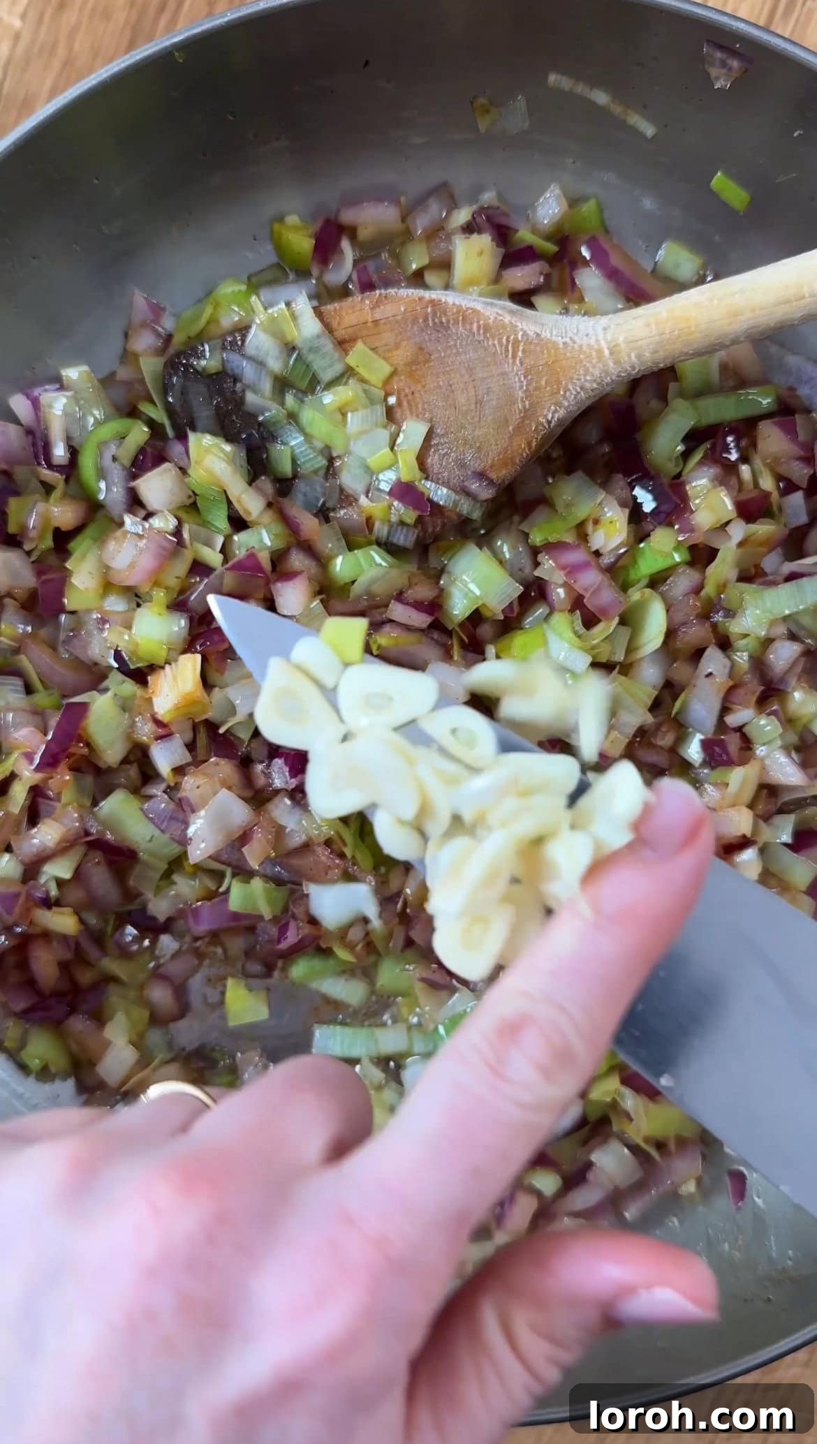 Finely chopped red onion and leeks sautéing in butter and pancetta oil, with minced garlic about to be added.