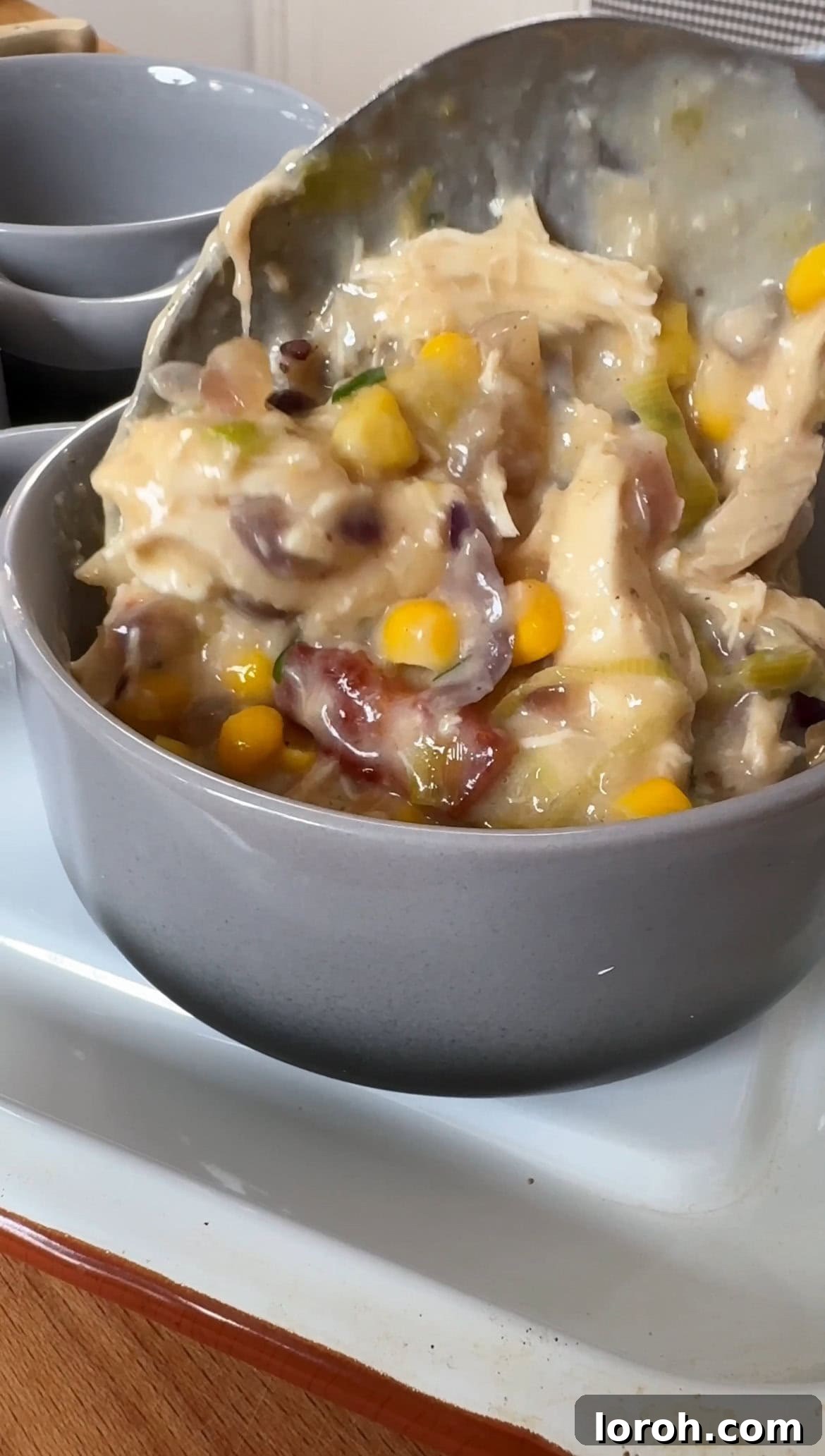 A creamy chicken, bacon, leek, and sweetcorn filling being spooned into individual ramekins, ready for the pastry topping.