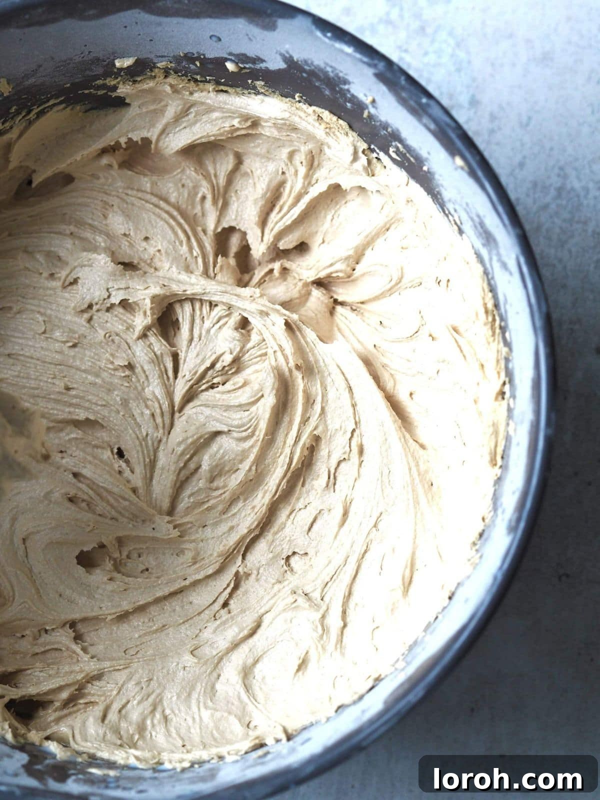 Creamy Biscoff buttercream frosting being whipped in a bowl with an electric mixer.