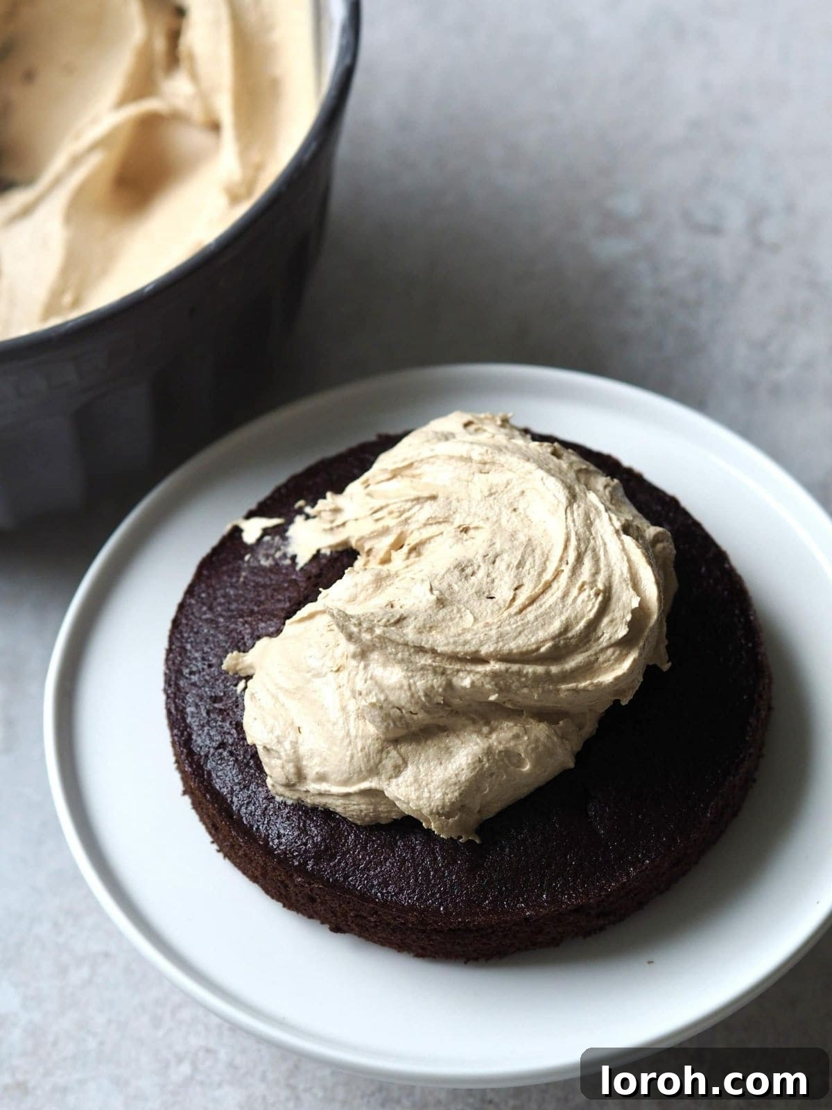 A layer of Biscoff buttercream being spread onto a chocolate cake tier.