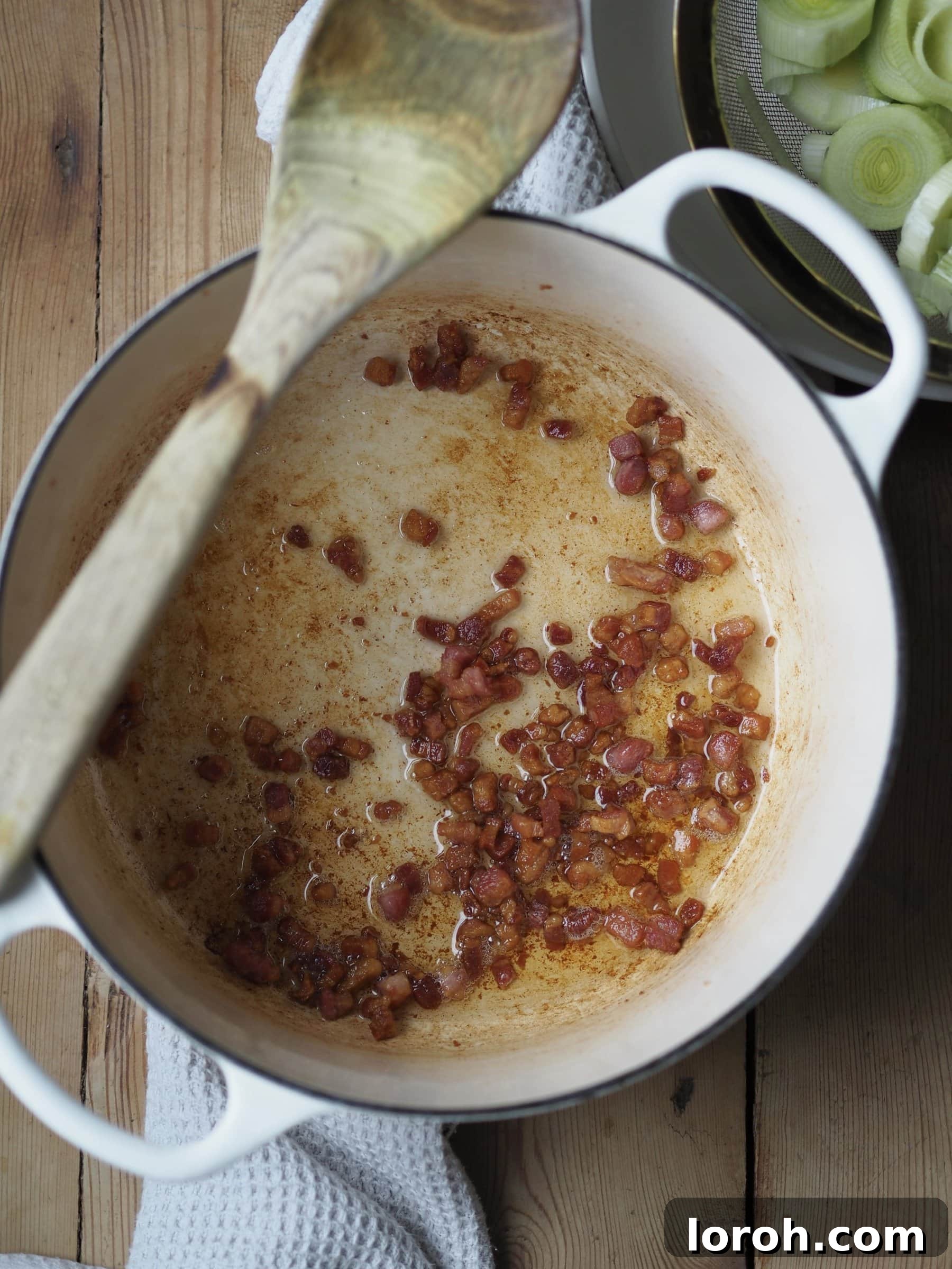Frying diced bacon in a pot until crisp.
