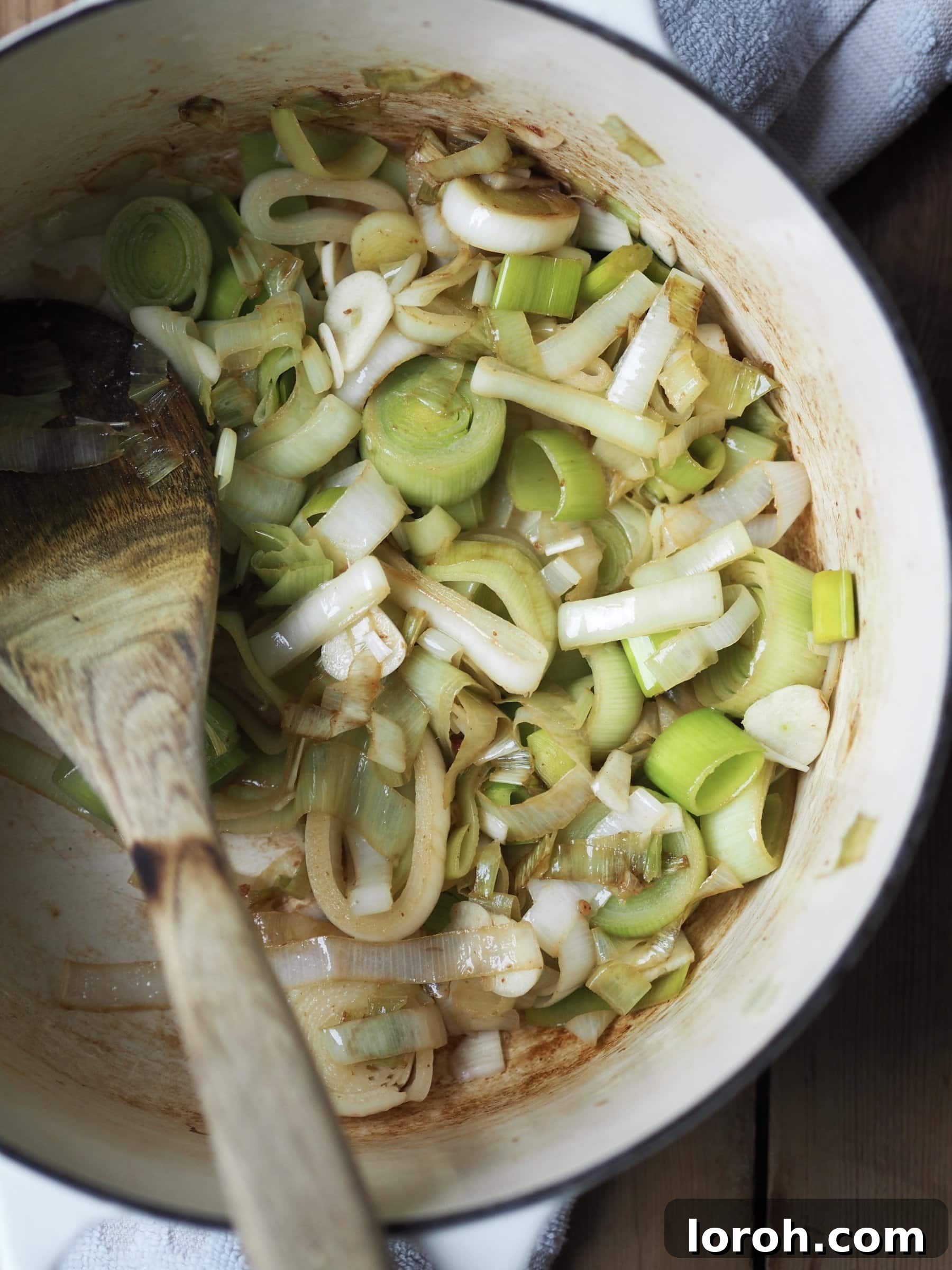 Sautéing diced leeks in bacon fat with garlic.