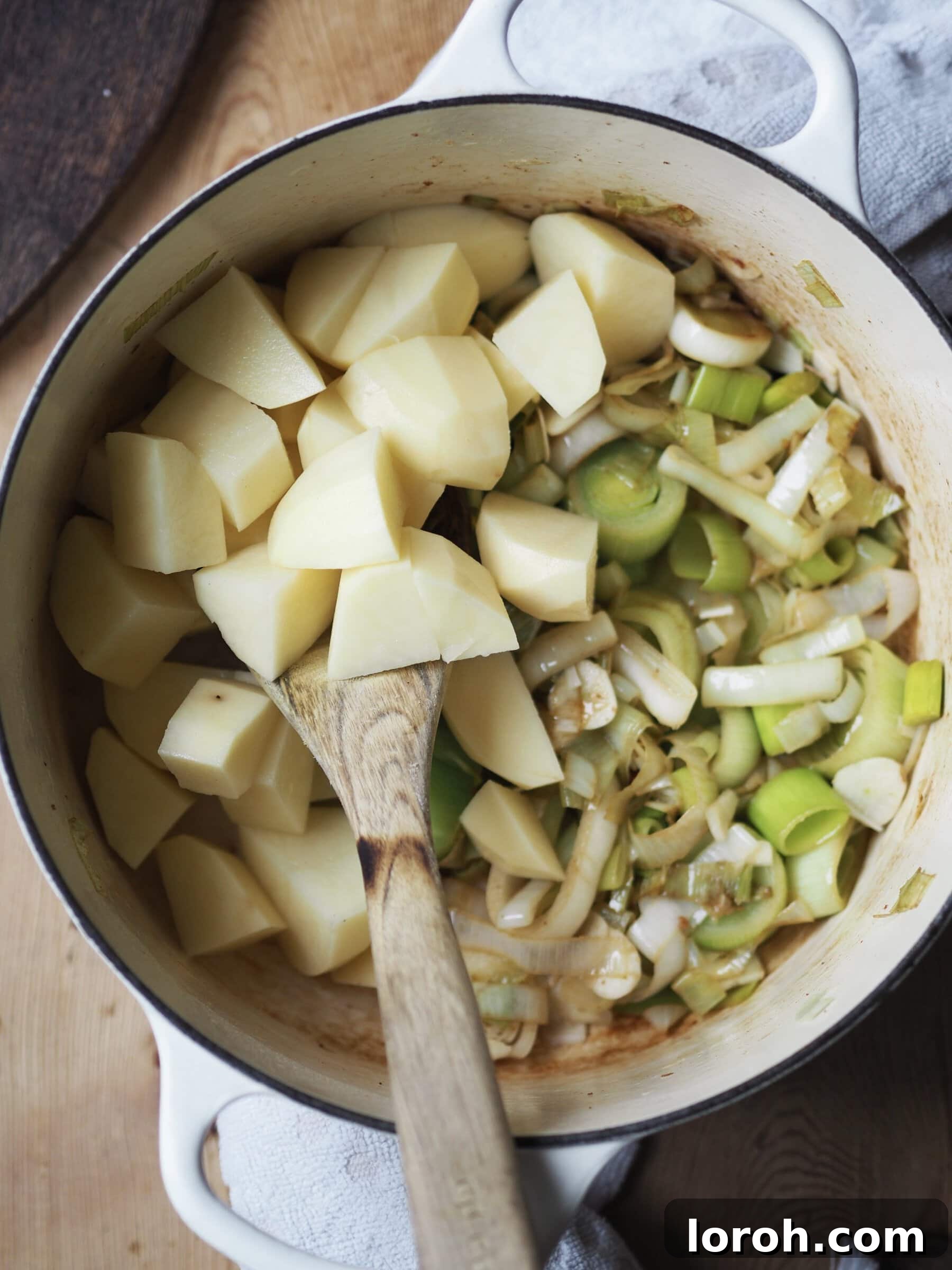Adding diced potatoes to the sautéed leeks and garlic.
