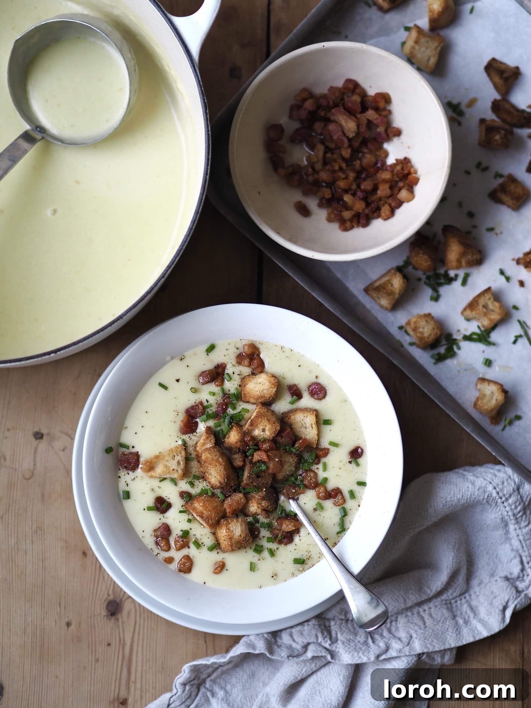 Serving Creamy Potato and Leek Soup with crispy bacon, chives, and croutons.