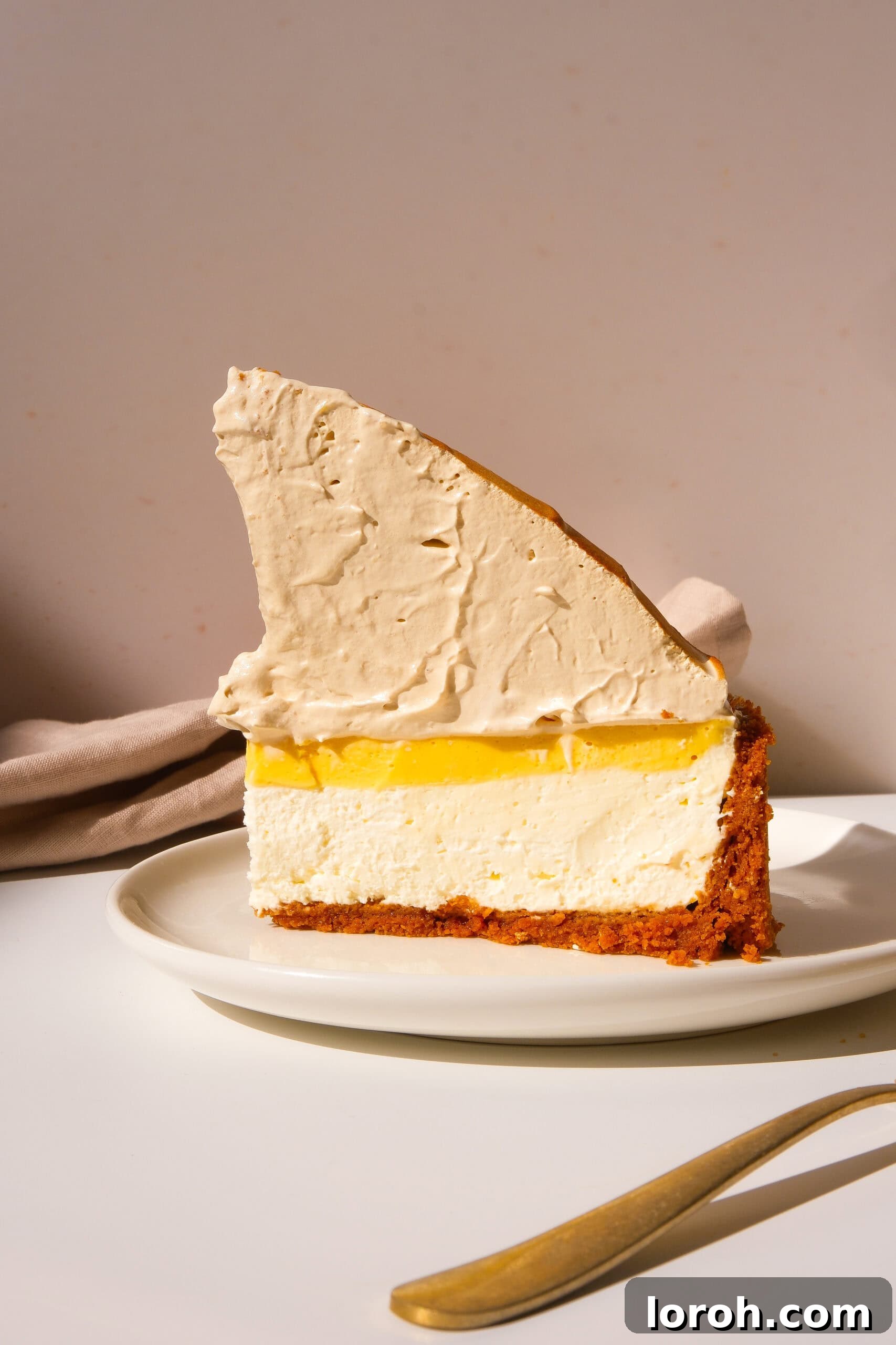 Zesty Lemon Meringue Delight 17 a perfect slice of lemon meringue cheesecake on a white plate