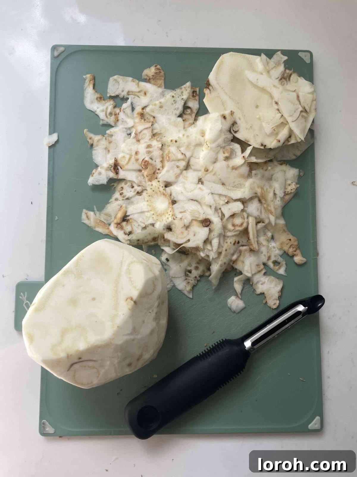 Zesty Celeriac Remoulade 7 Hands carefully peeling the rough, brown skin from a celeriac bulb using a sharp knife, revealing the clean, white flesh underneath.