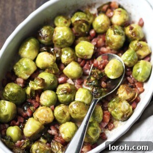 White serving dish with whole roasted sprouts with bacon lardons.
