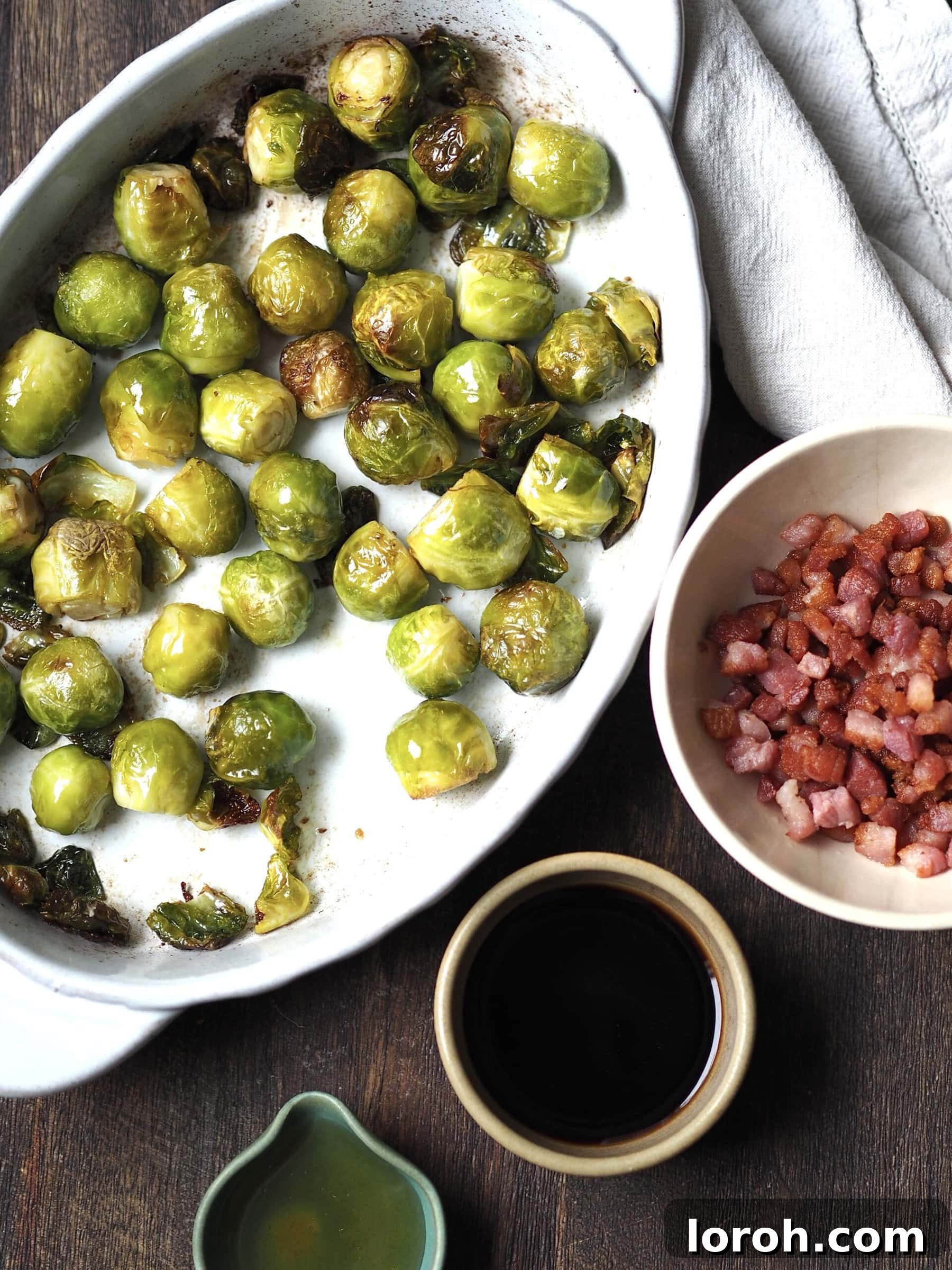 Roasted sprouts next to bowls of cooked bacon, balsamic vinegar and honey for glazing.
