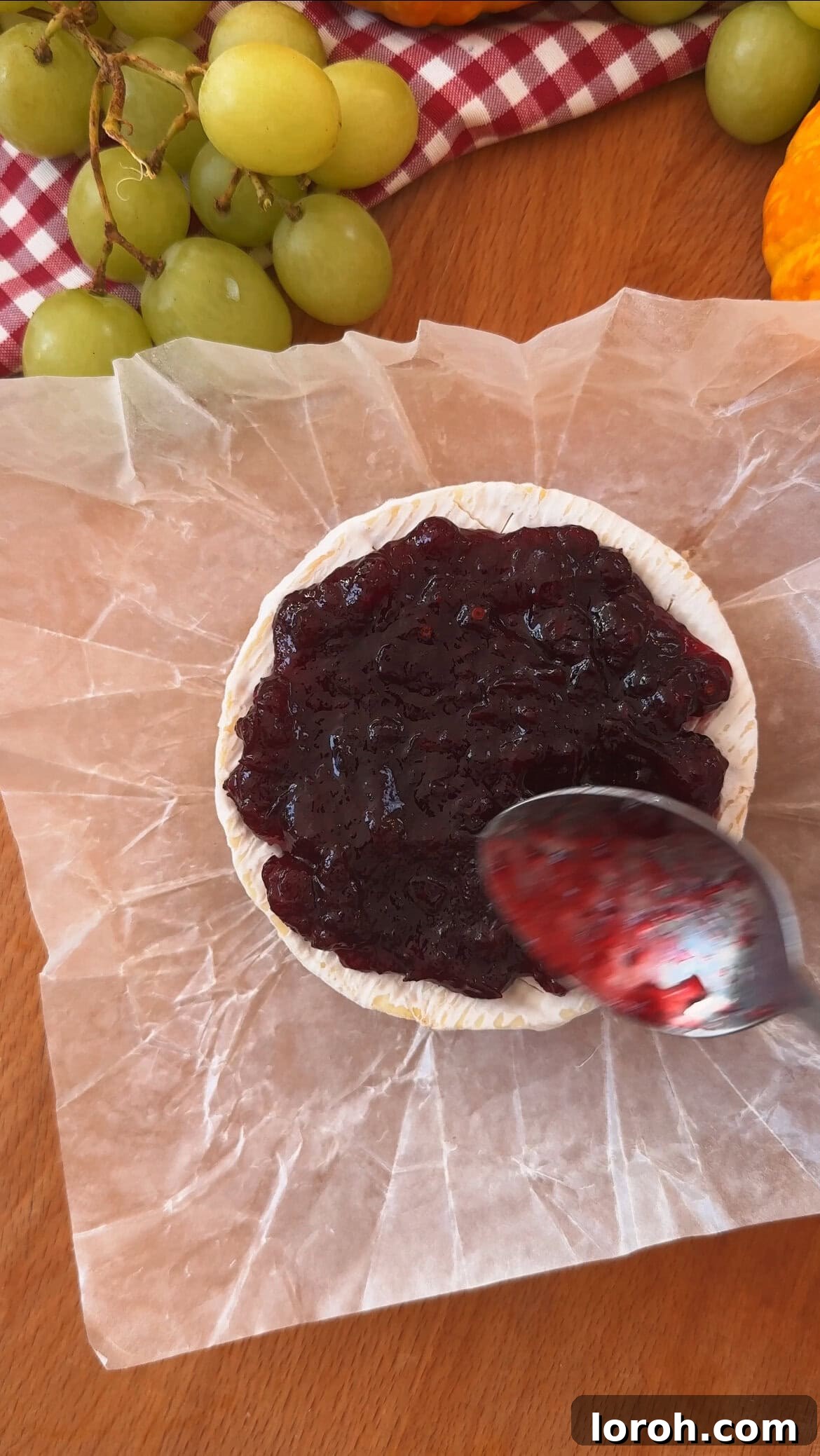 Garlic Cranberry Baked Brie in a Pumpkin Puff Pastry 5 Inserting garlic slices into the scored brie and spreading cranberry sauce over it.