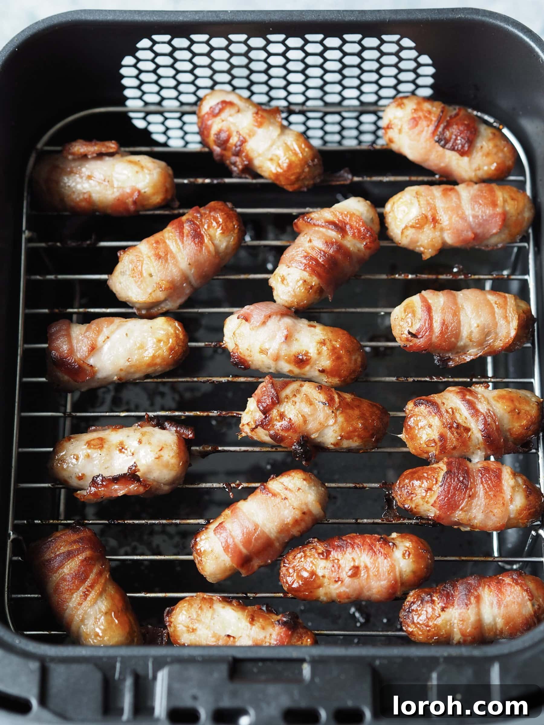 Golden Air Fryer Sausage Bites 3 Close up of cooked pigs in blankets in the air fryer.