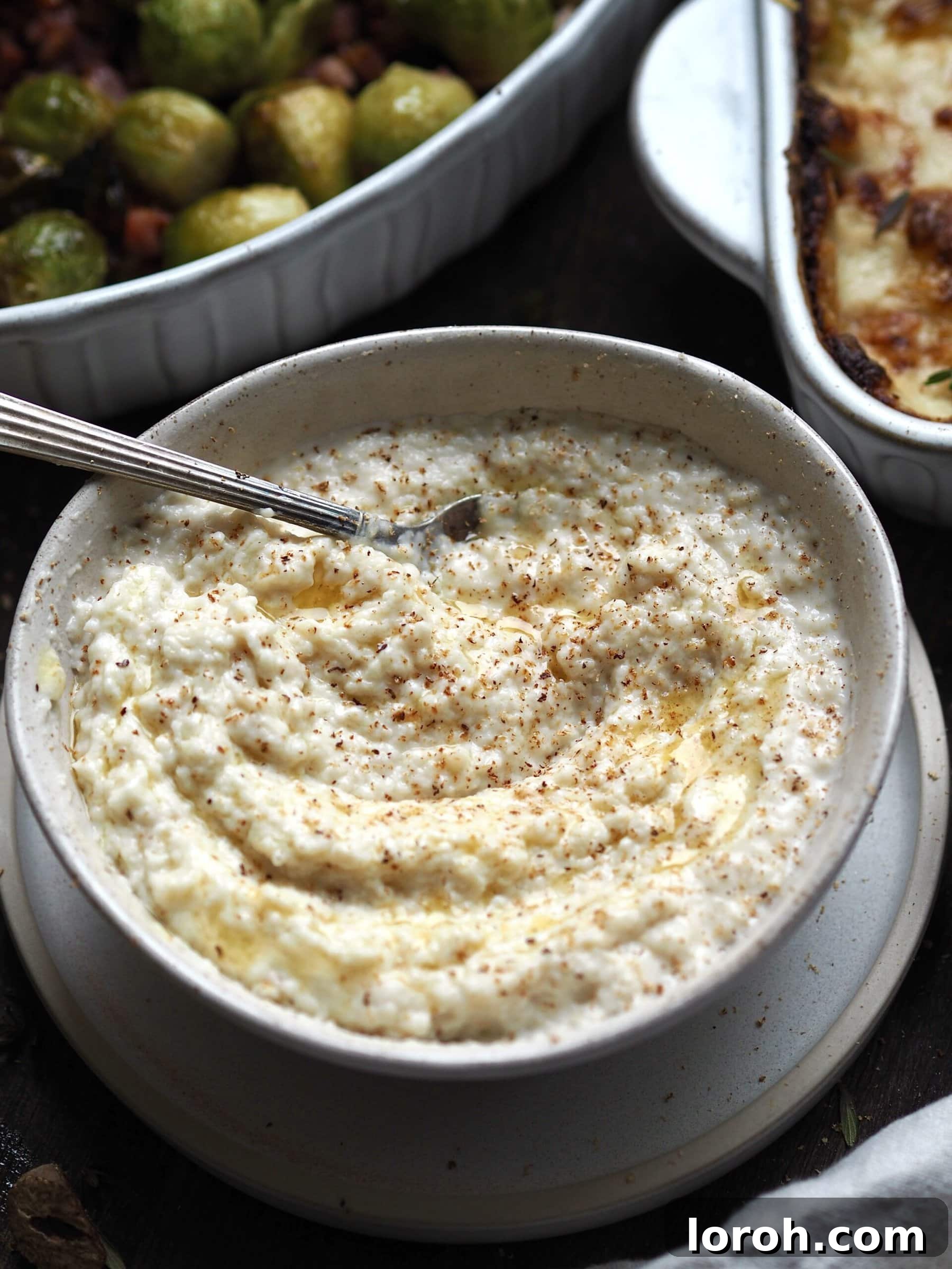 Bowl of bread sauce with dishes of bacon sprouts and cheesy leeks in the background.