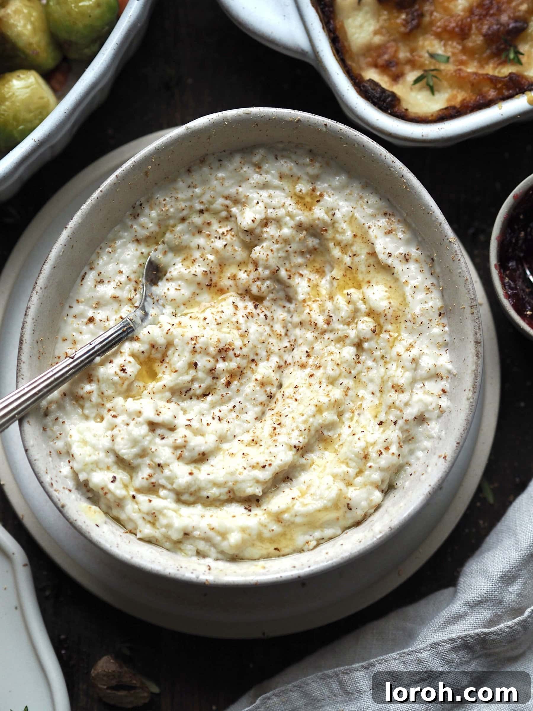 Close up of a bowl of bread sauce topped with melted butter and grated nutmeg. 