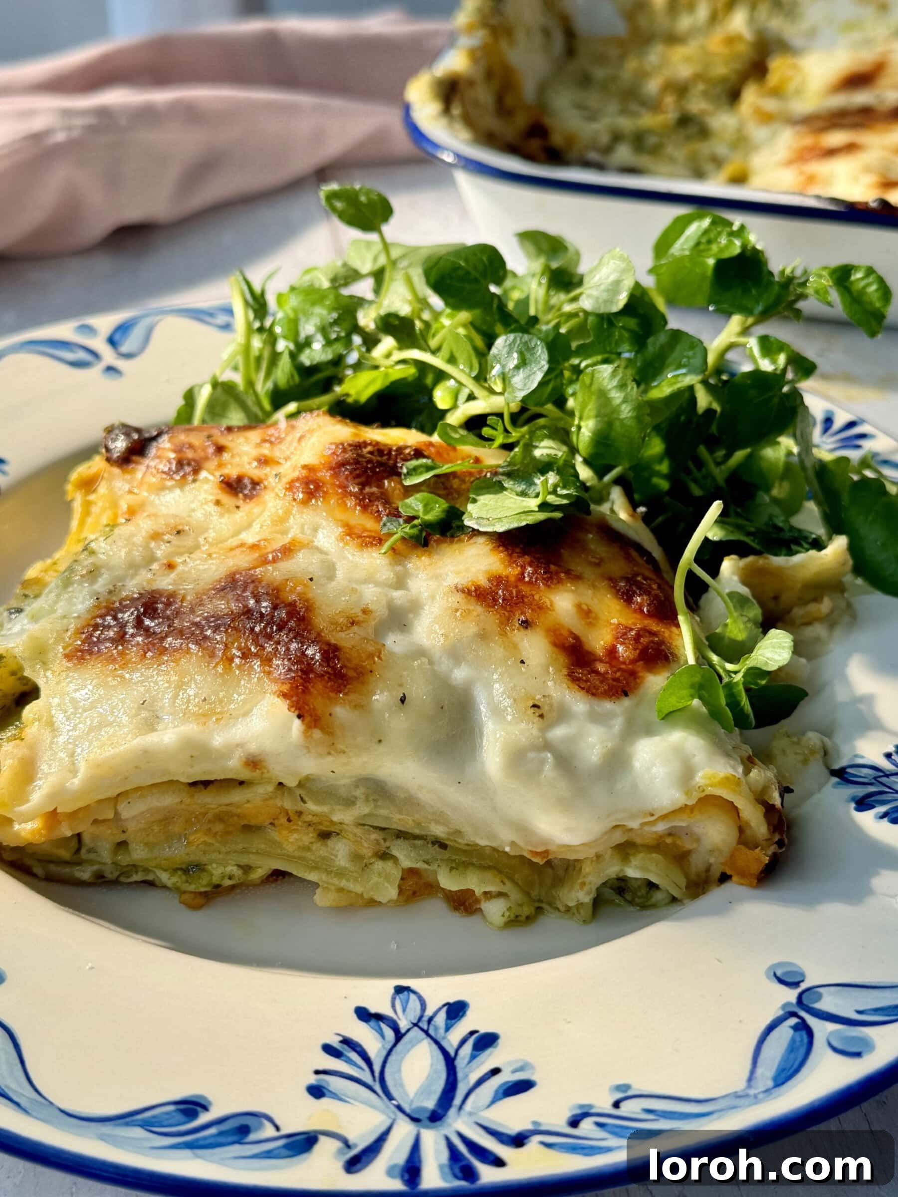 Basil Bliss Lasagna Bake 2 A perfectly portioned slice of Pesto Lasagne with butternut squash on a white plate, ready to be enjoyed.