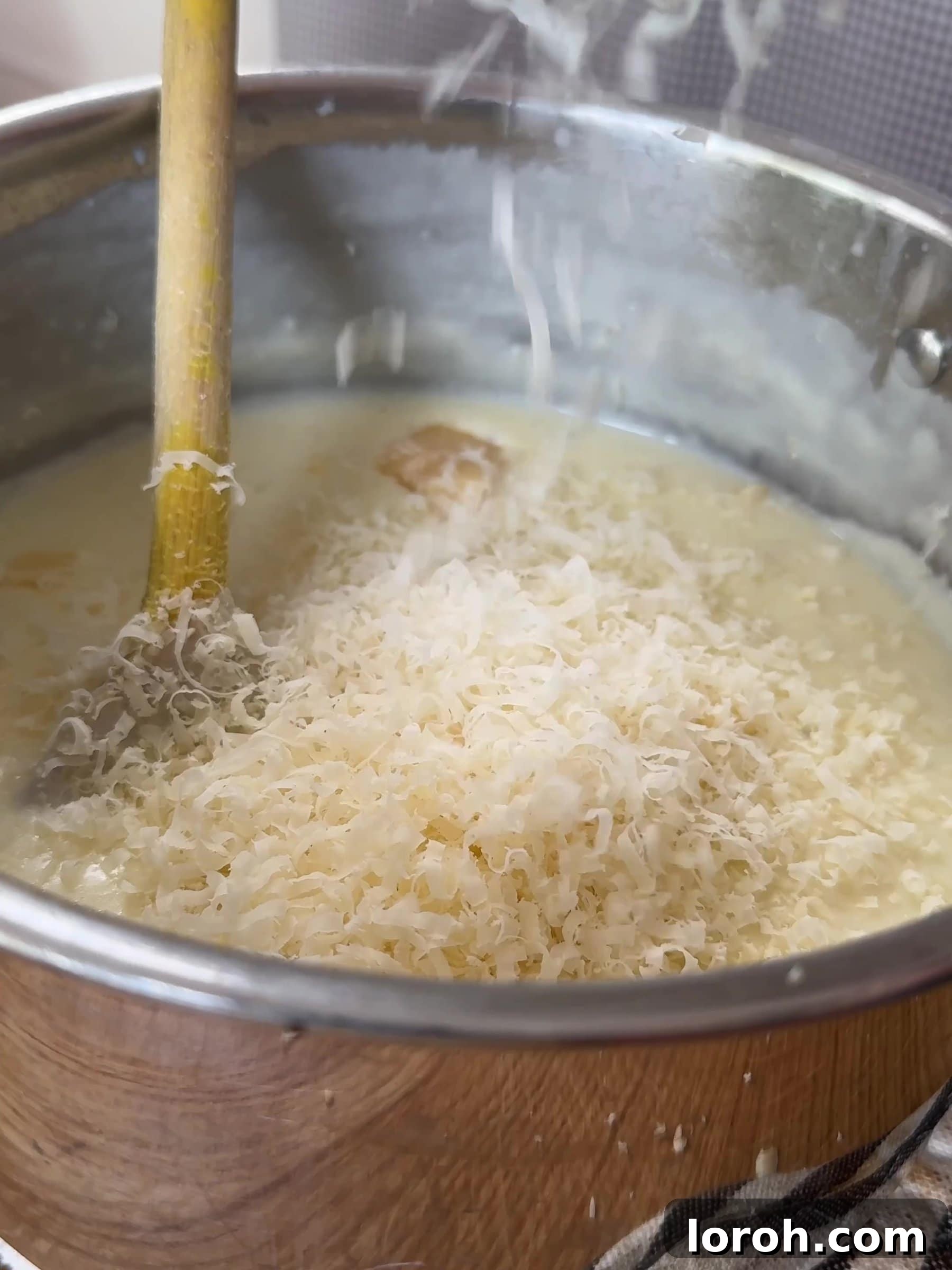 Basil Bliss Lasagna Bake 9 Adding grated cheese to the thickened béchamel sauce.