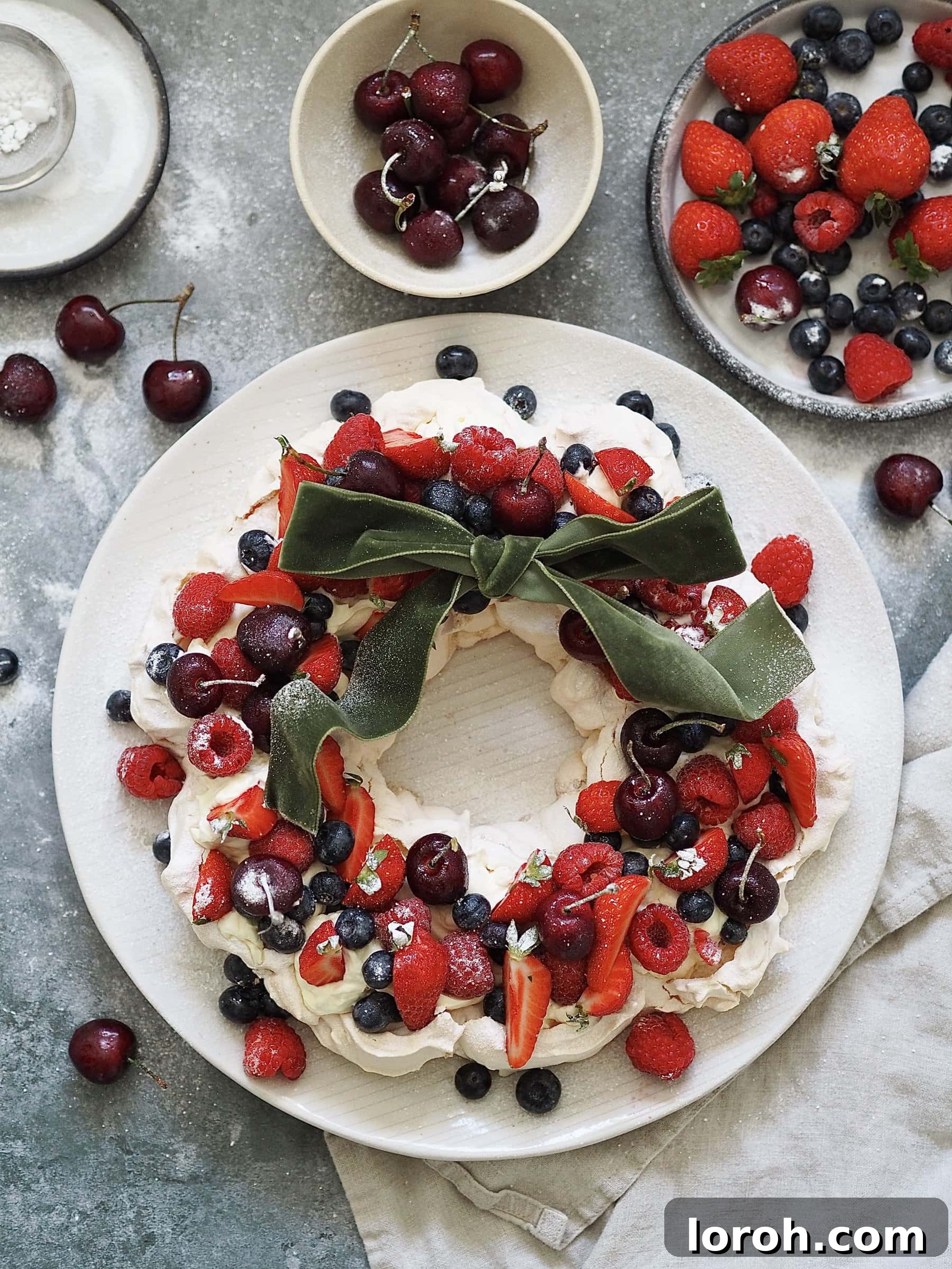 Festive Meringue Wreath 17 Christmas Pavlova on a plate with bowls of berries