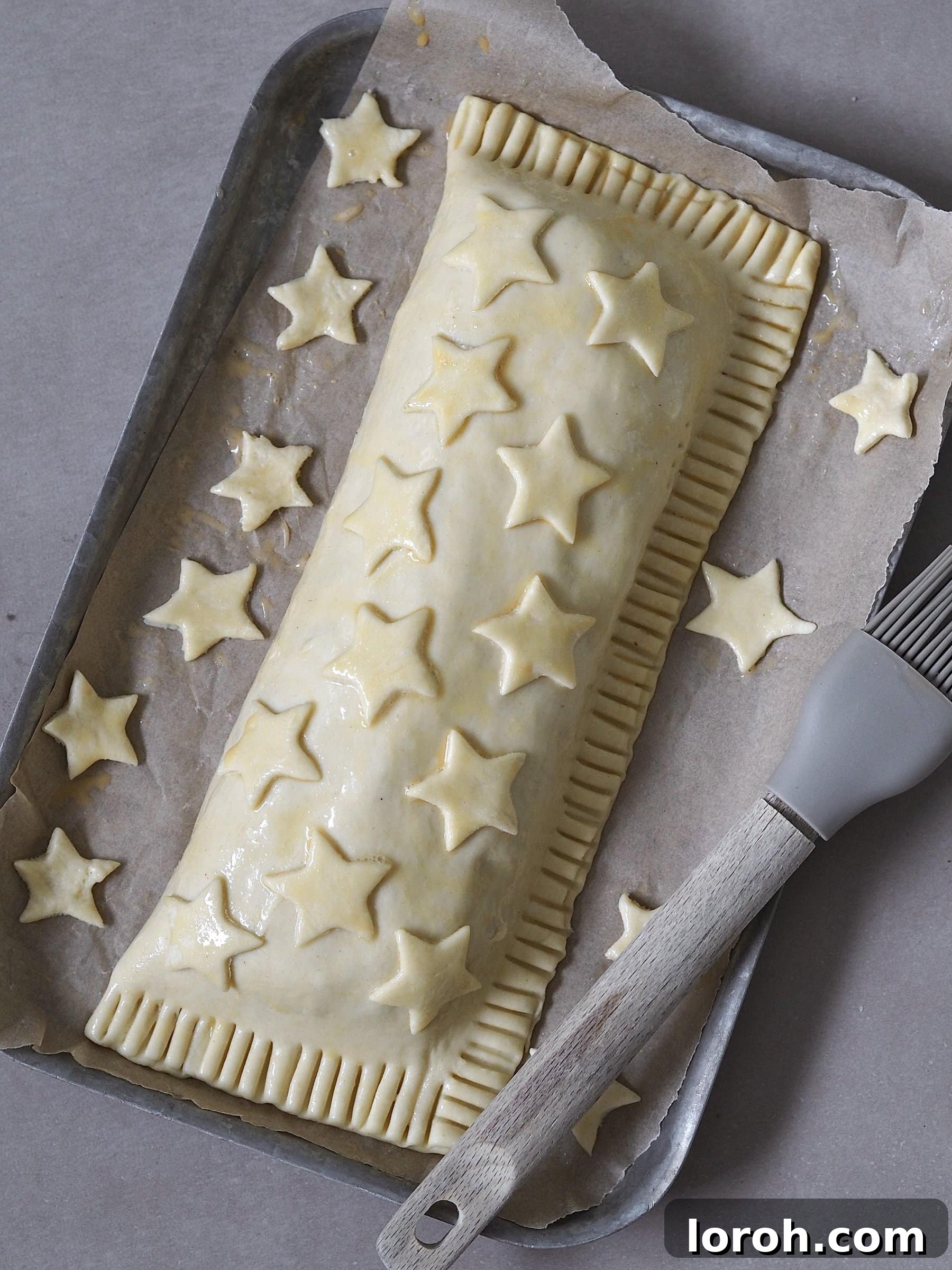 Decorating the Nut Roast Wellington with pastry stars and brushing with egg wash