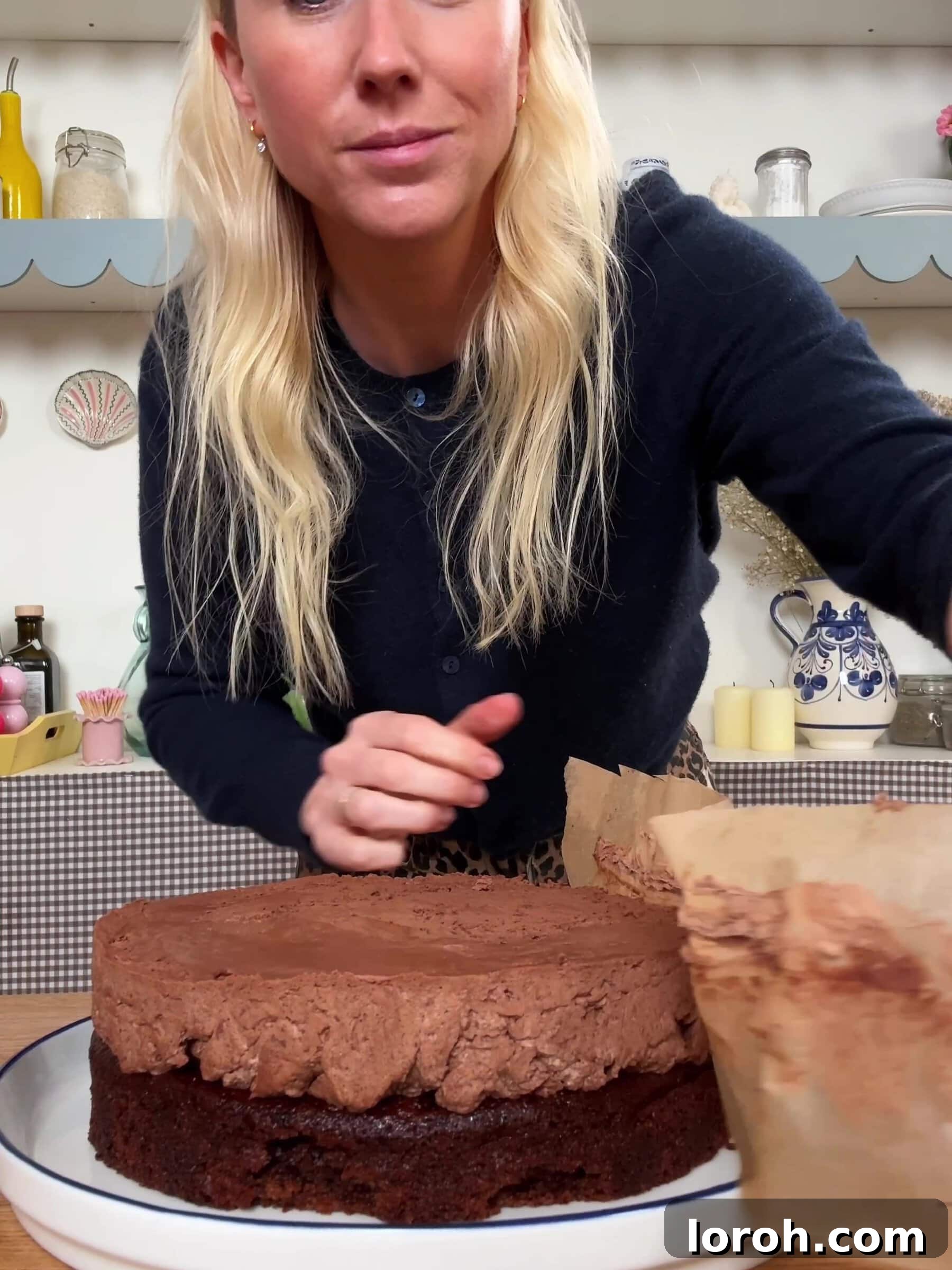 Carefully peeling baking paper from the chilled chocolate mousse layer of the cake.