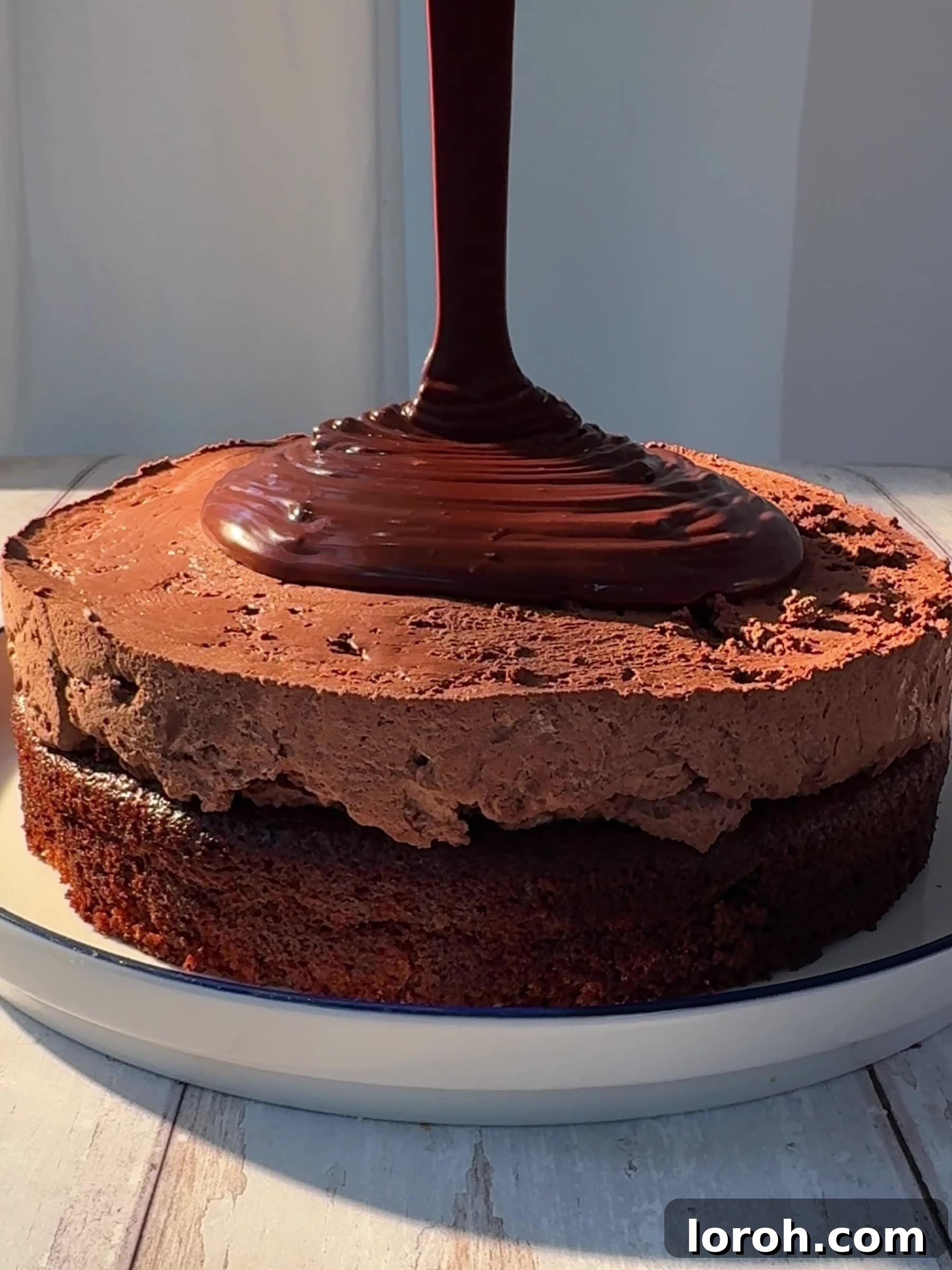 Pouring the smooth, glossy chocolate ganache over the center of the chocolate mousse cake.